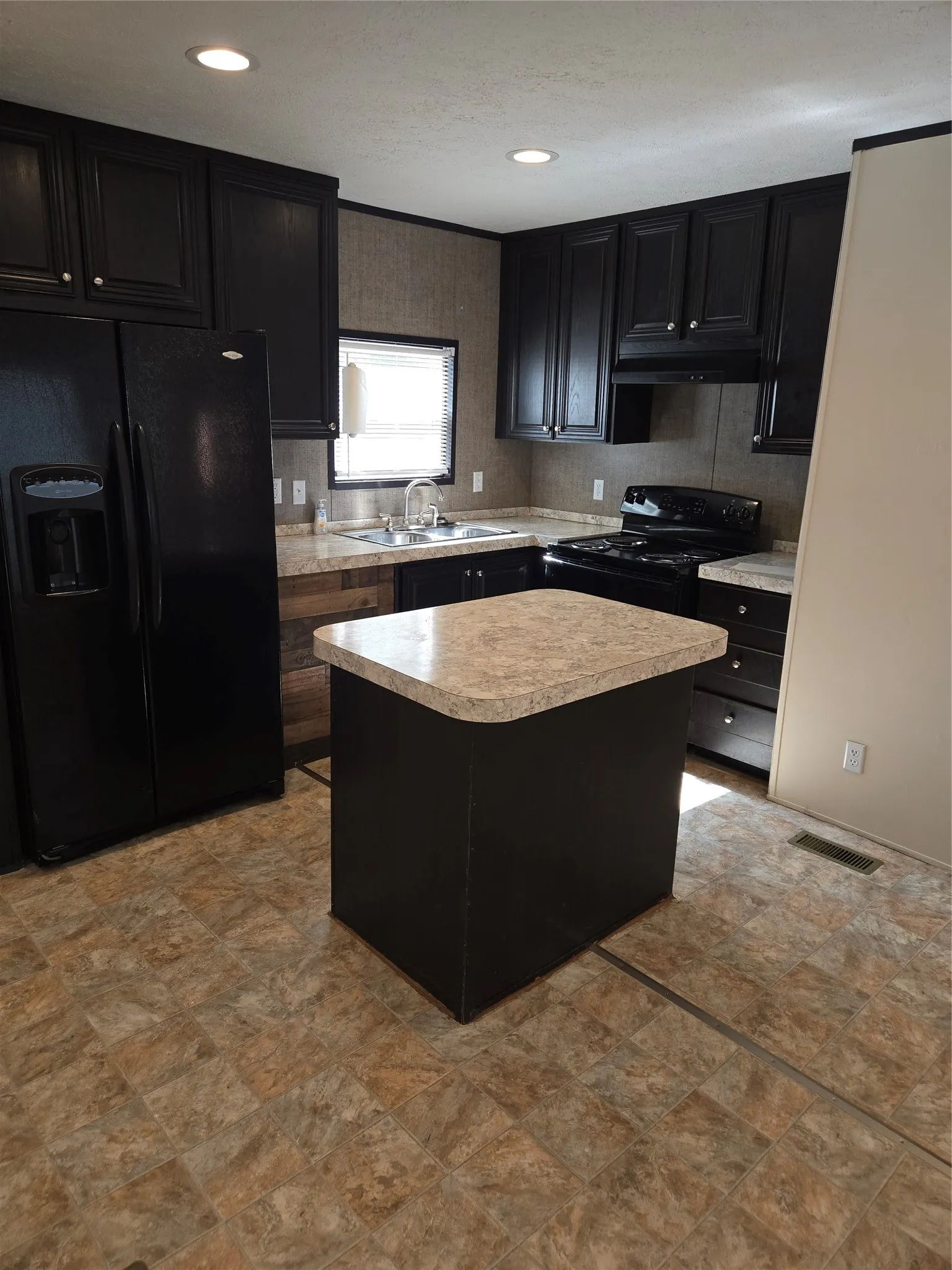 Kitchen featuring dark cabinetry, laminate countertops, and an integrated kitchen island
