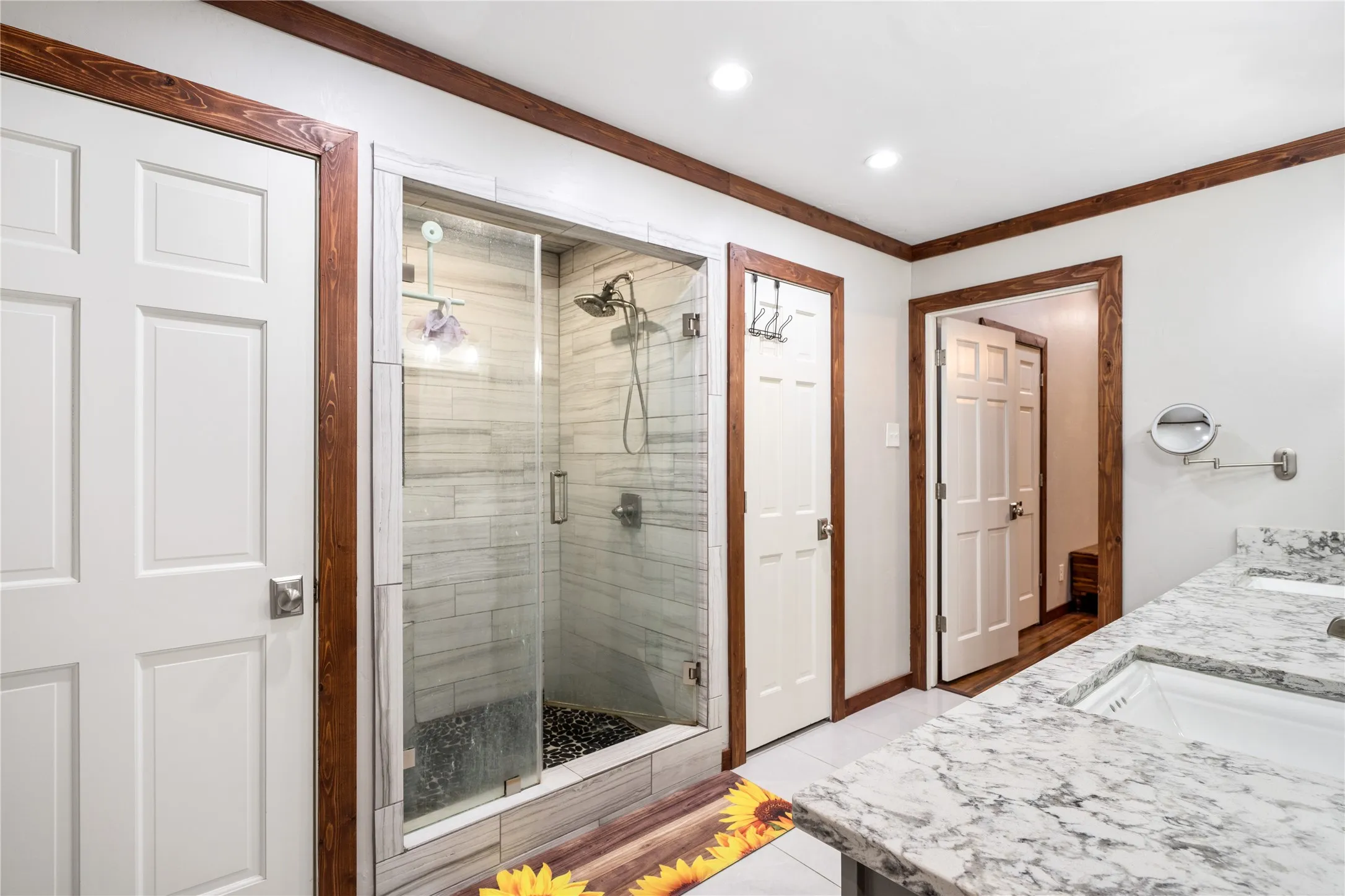 Glass-enclosed shower featuring large format tile surround and a river rock base