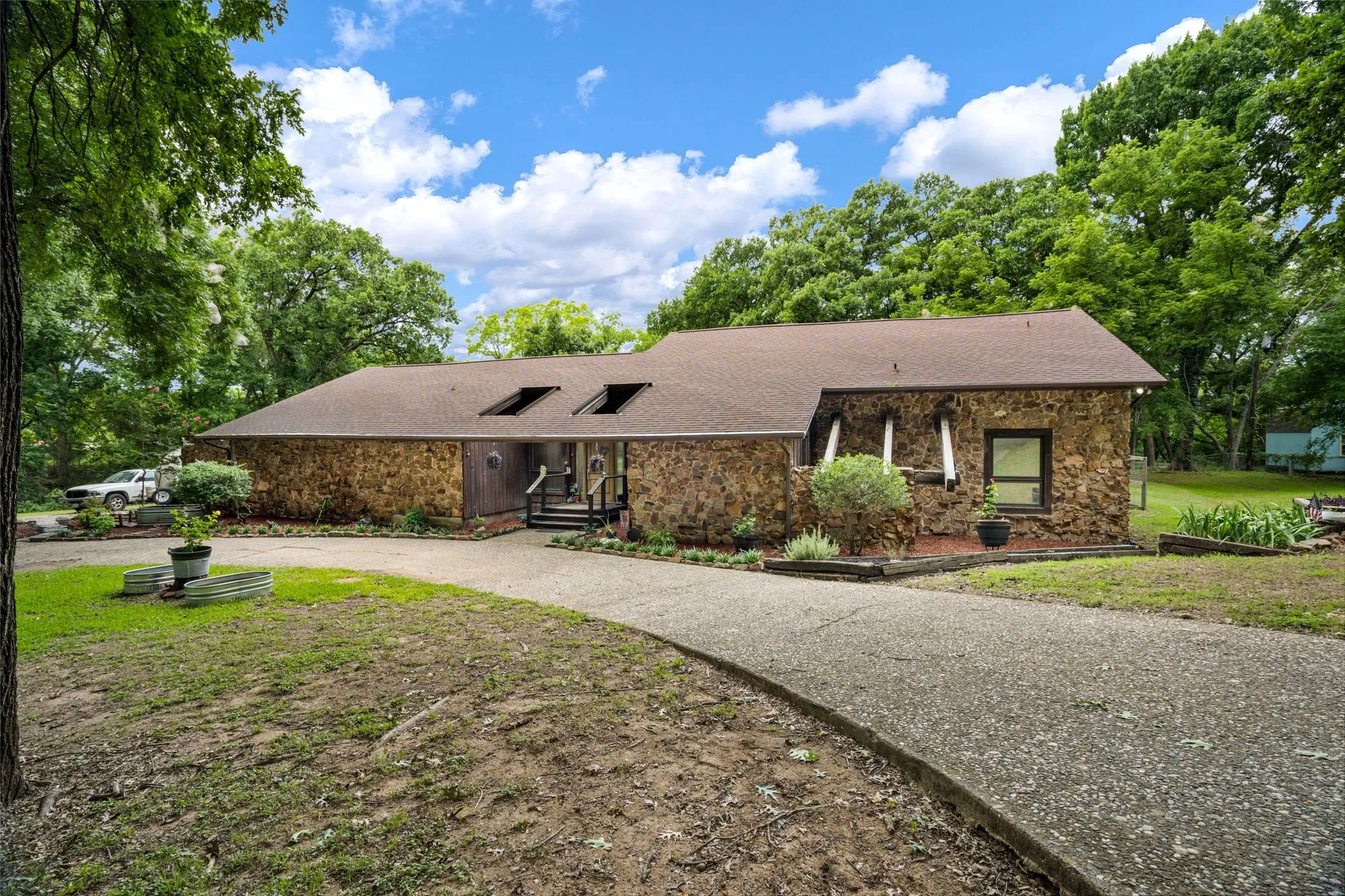 Stone exterior featuring a dark asphalt shingle roof with skylights