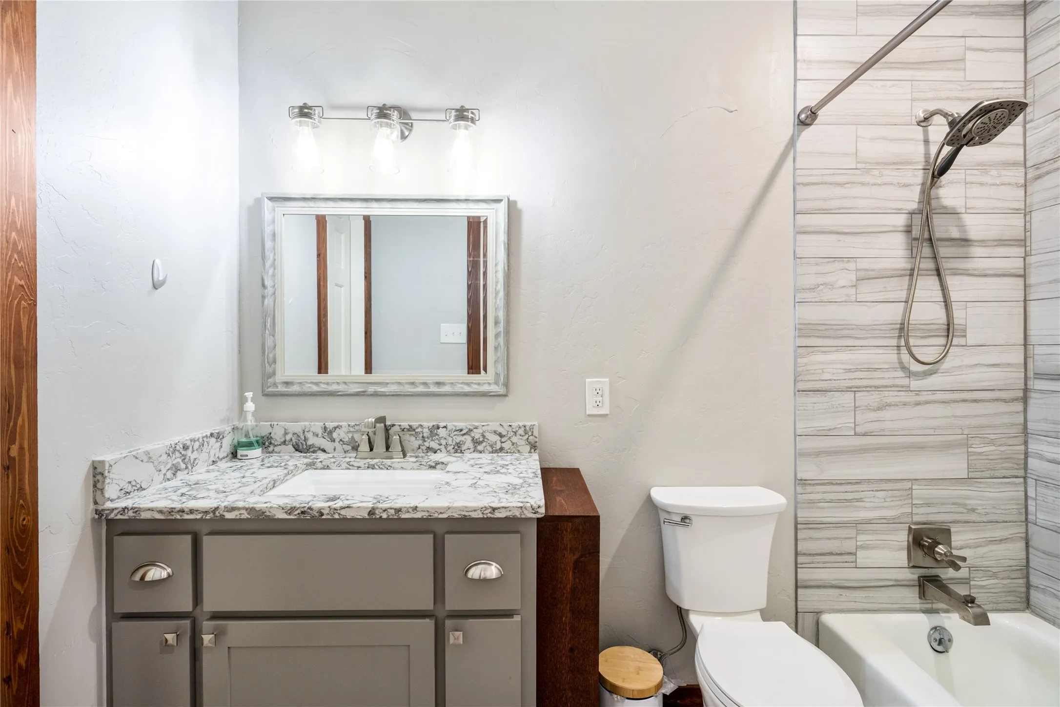Bathroom featuring a gray vanity with a stone countertop, an undermount sink, and a brushed nickel faucet