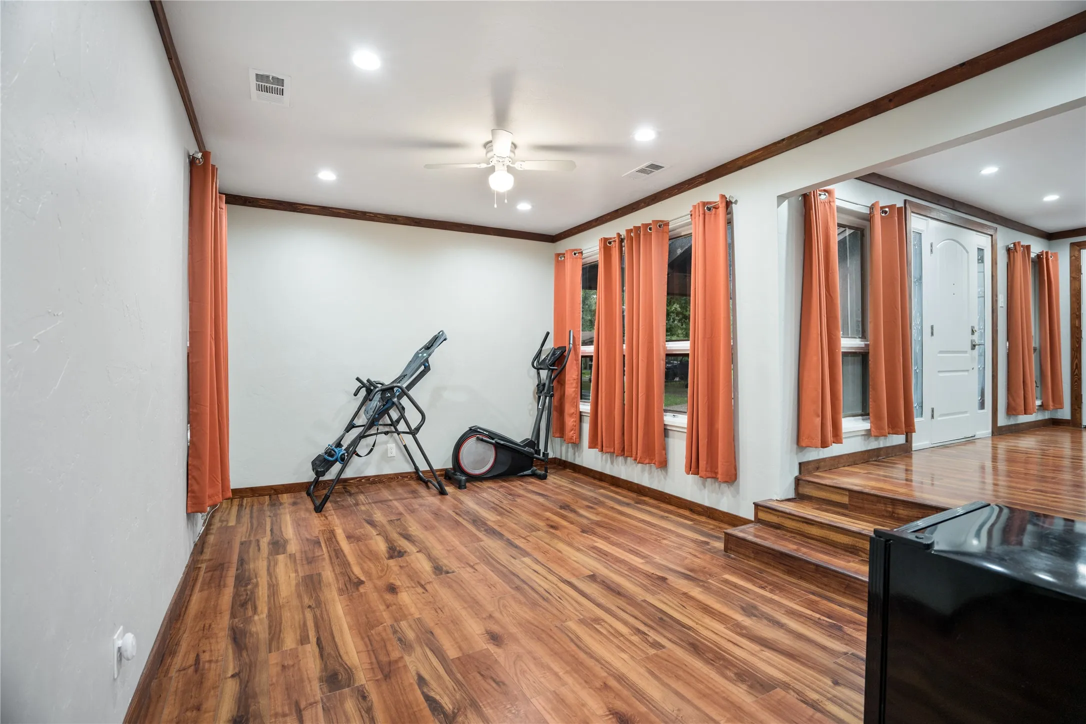 Spacious room featuring wood-finish flooring, recessed lighting, a ceiling fan, and multiple windows