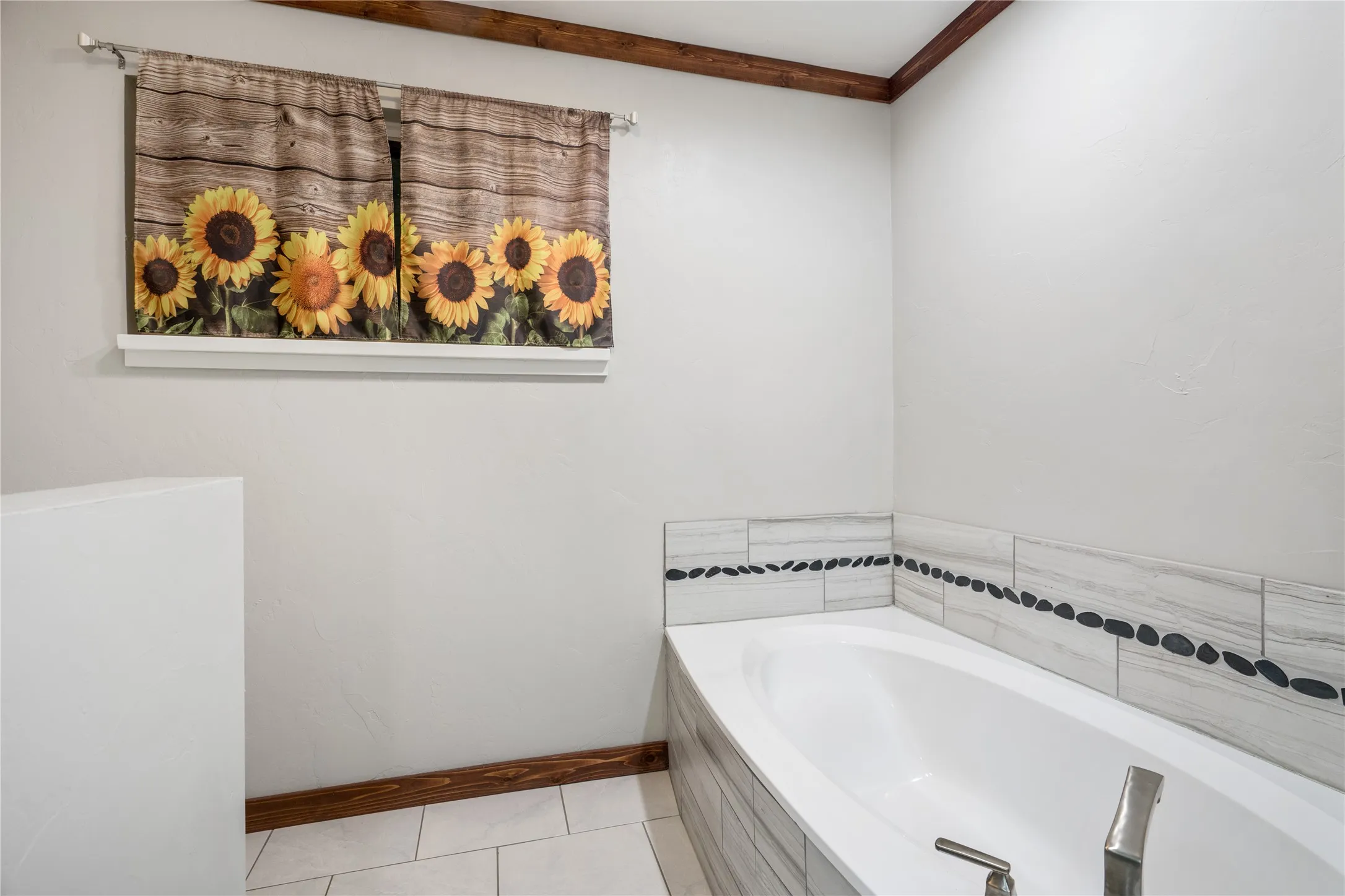 White soaking tub with tiled surround featuring stone accents