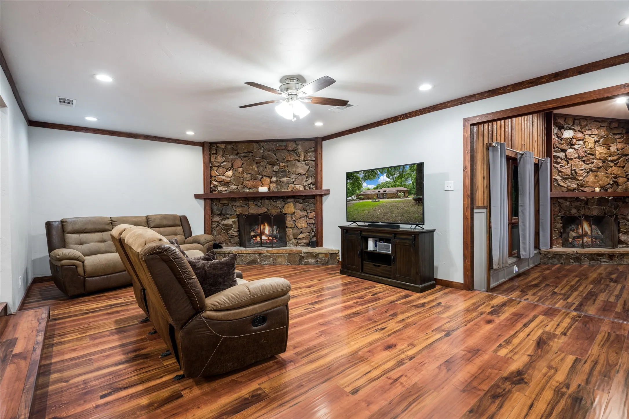 Spacious room featuring wood-finish flooring, a stone fireplace with a wood mantle, recessed lighting, and a ceiling fan