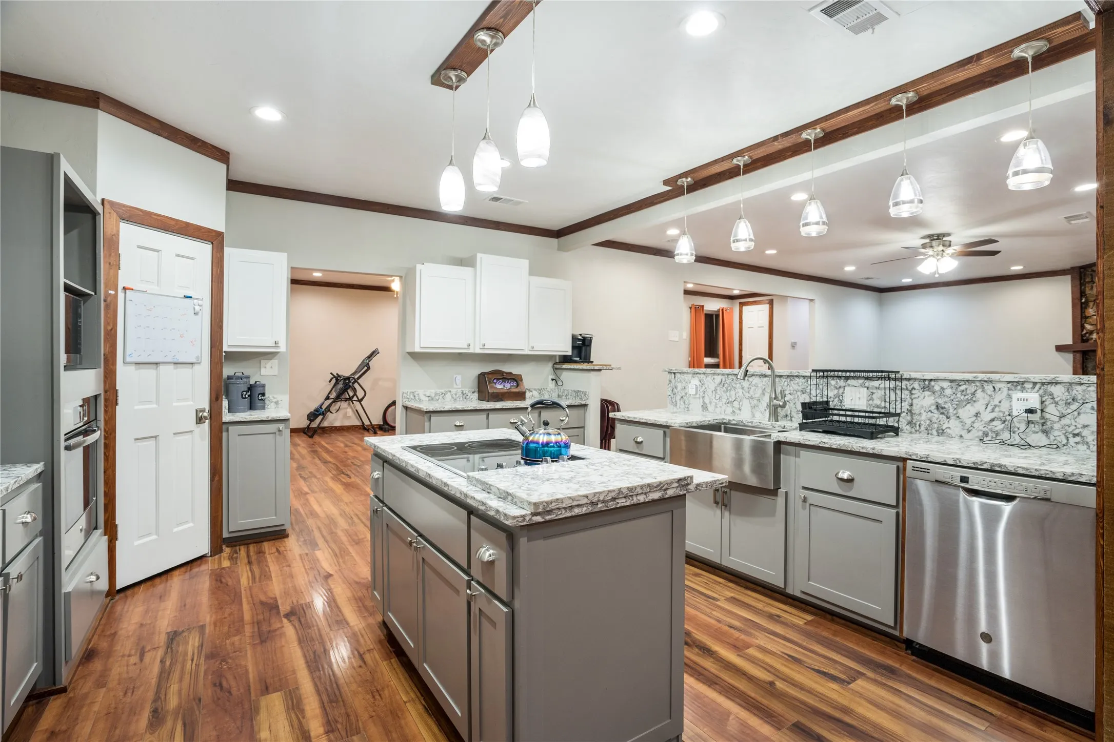 Kitchen featuring wood-finish flooring, two-tone cabinetry, stainless steel appliances, a center island with sink, and granite countertops with full-height backsplash