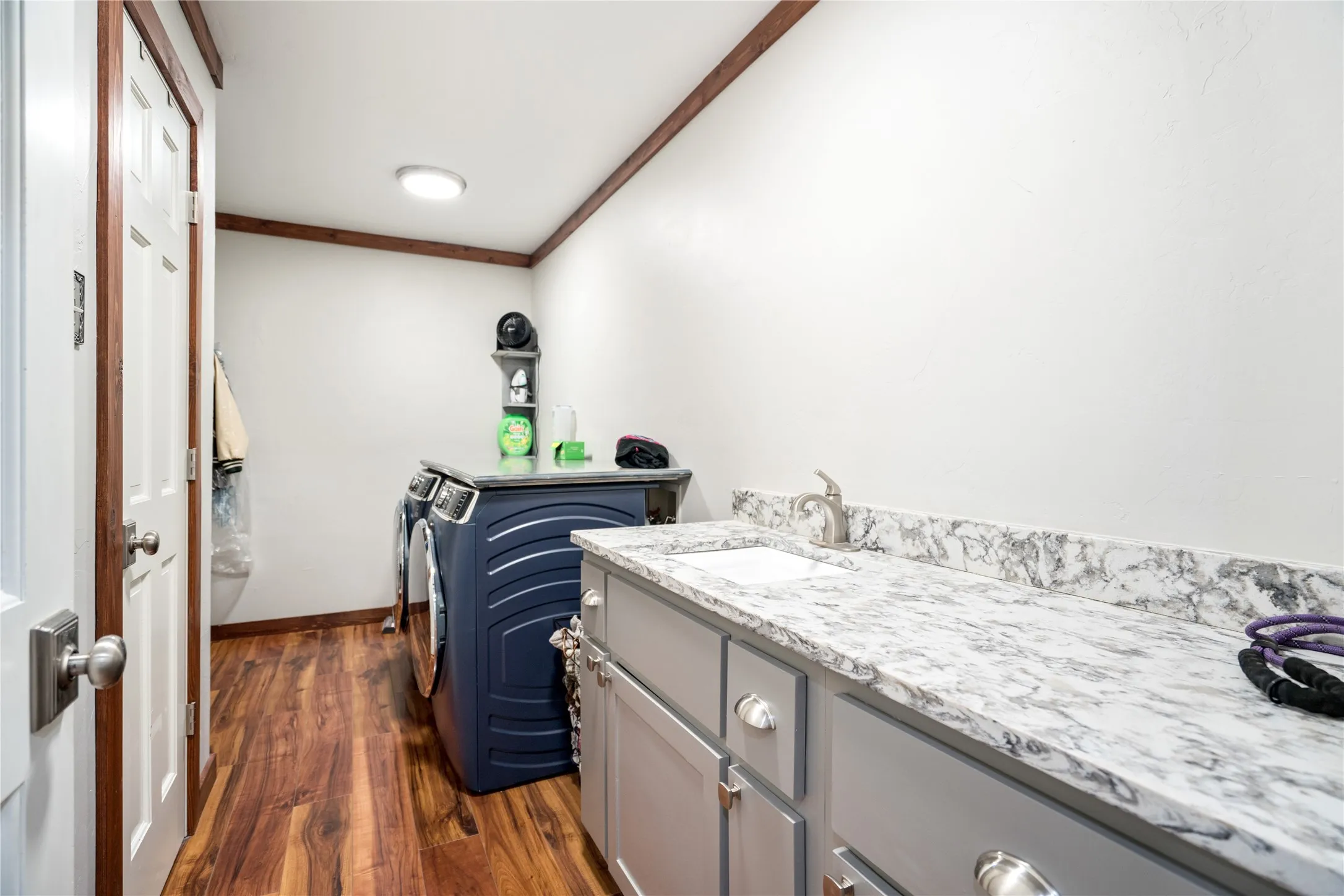 Laundry area featuring wood-finish flooring and a white ceiling with recessed lighting