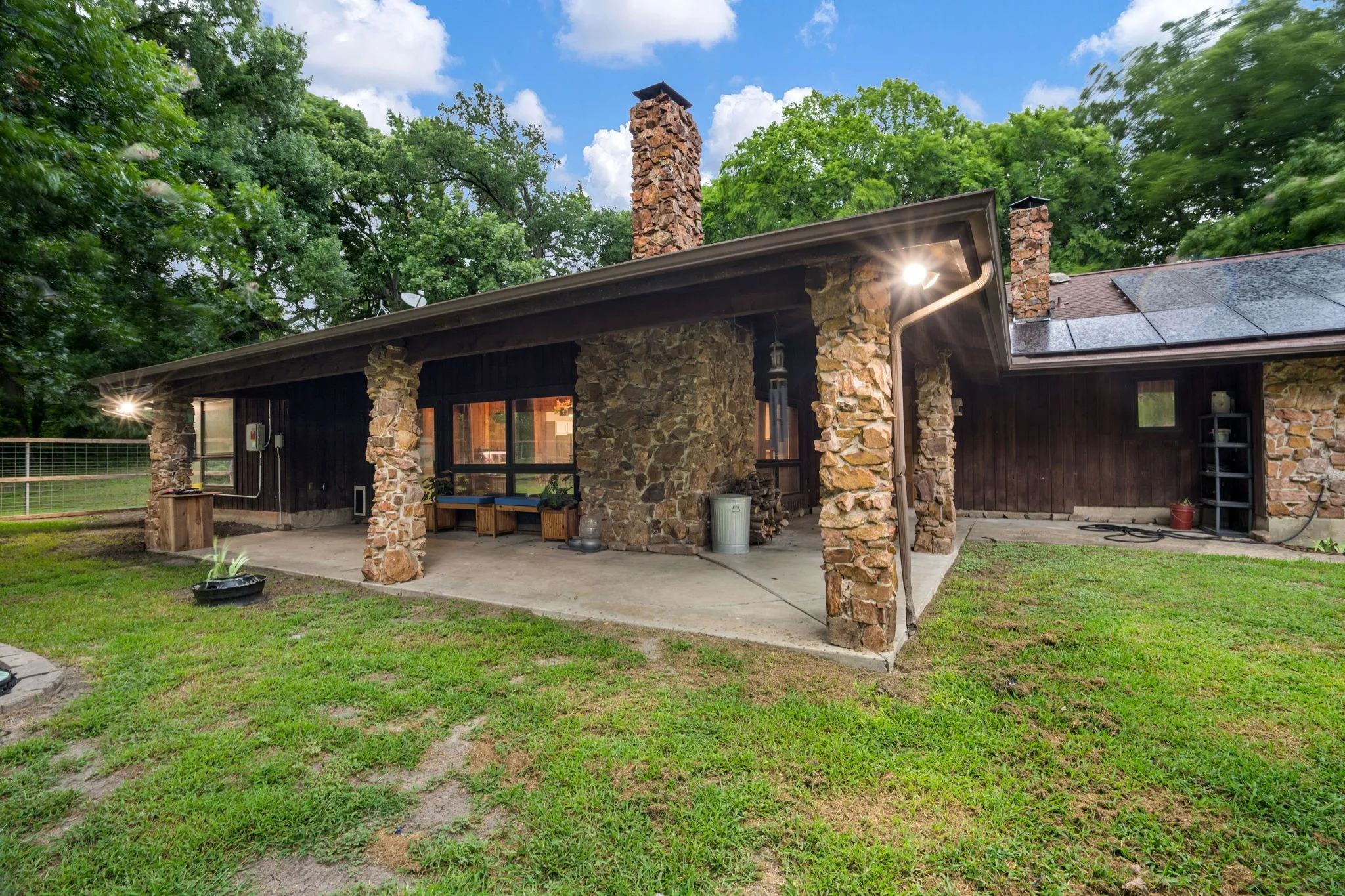 Stone veneer exterior with a covered patio and concrete flooring