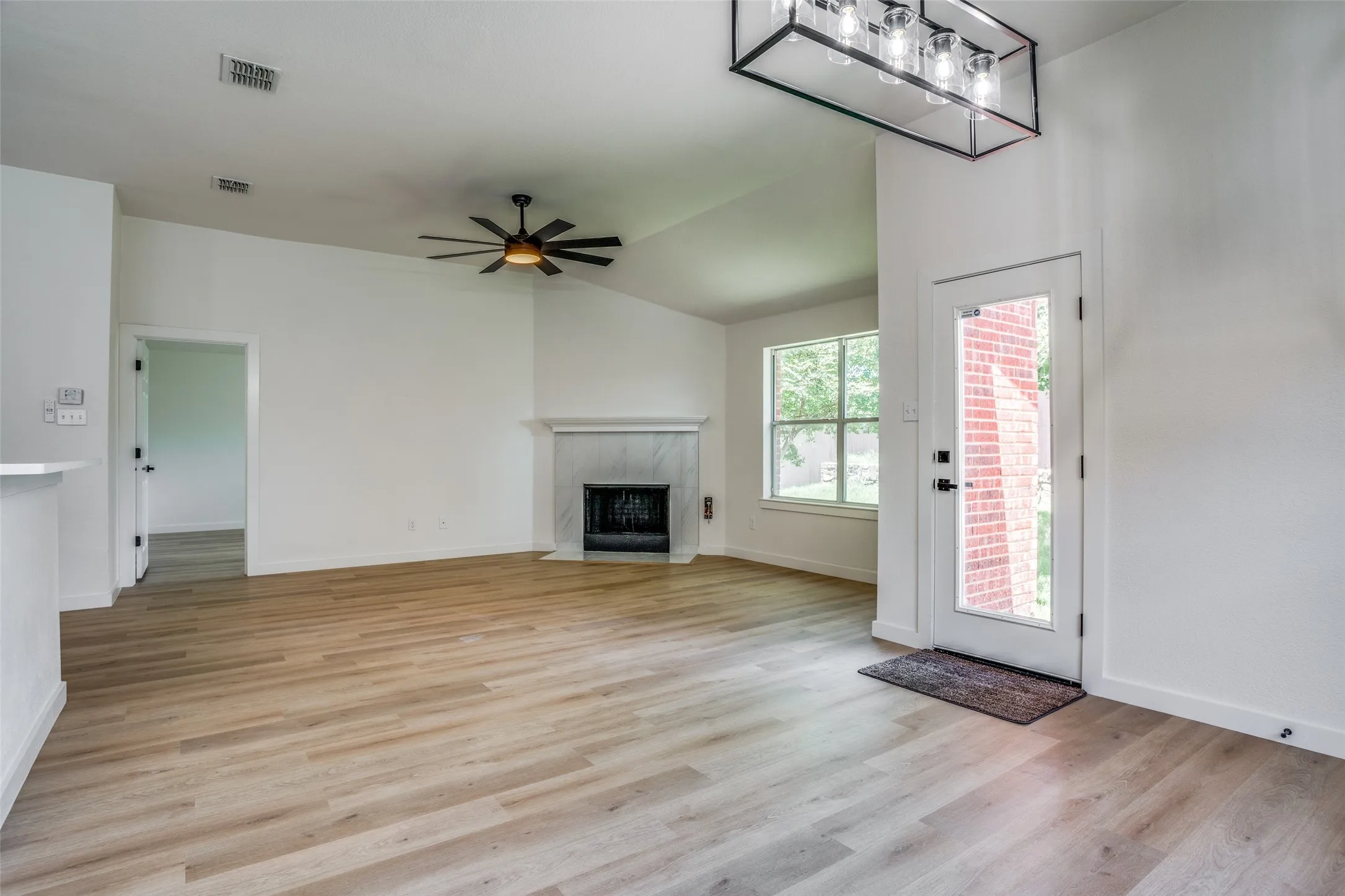 Unfurnished living room featuring a high end fireplace, ceiling fan, vaulted ceiling, and light wood-type flooring