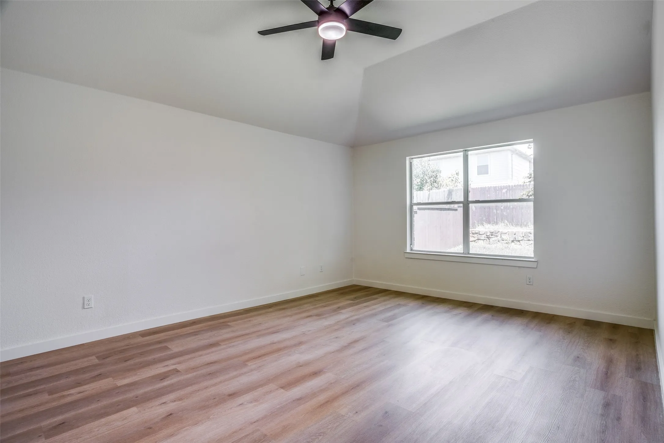 Spare room featuring hardwood / wood-style flooring, lofted ceiling, and ceiling fan