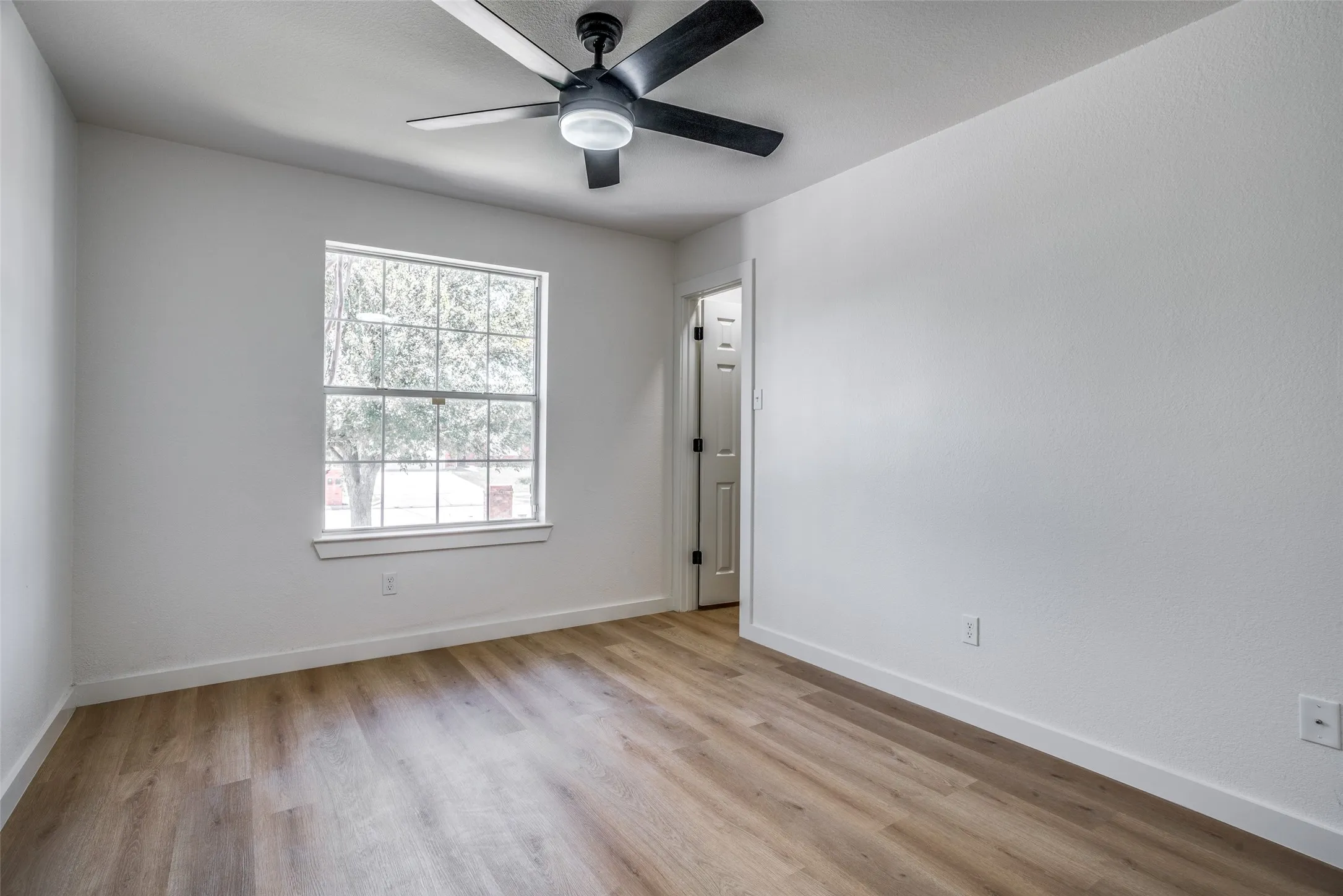 Empty room with ceiling fan and light hardwood / wood-style flooring