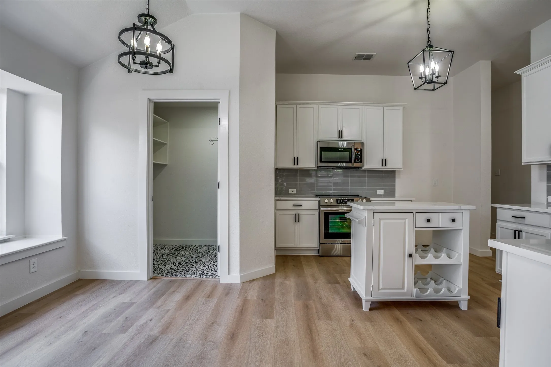 Kitchen featuring tasteful backsplash, white cabinetry, a center island, appliances with stainless steel finishes, and pendant lighting