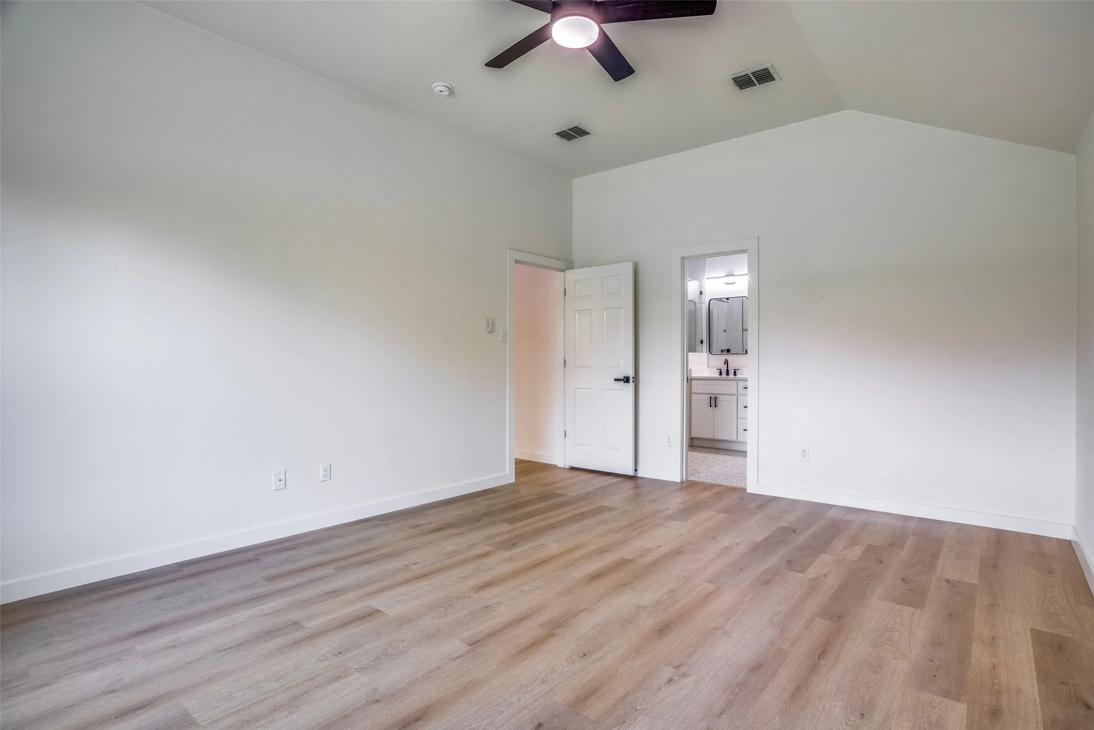 Unfurnished room with ceiling fan, vaulted ceiling, and light hardwood / wood-style flooring