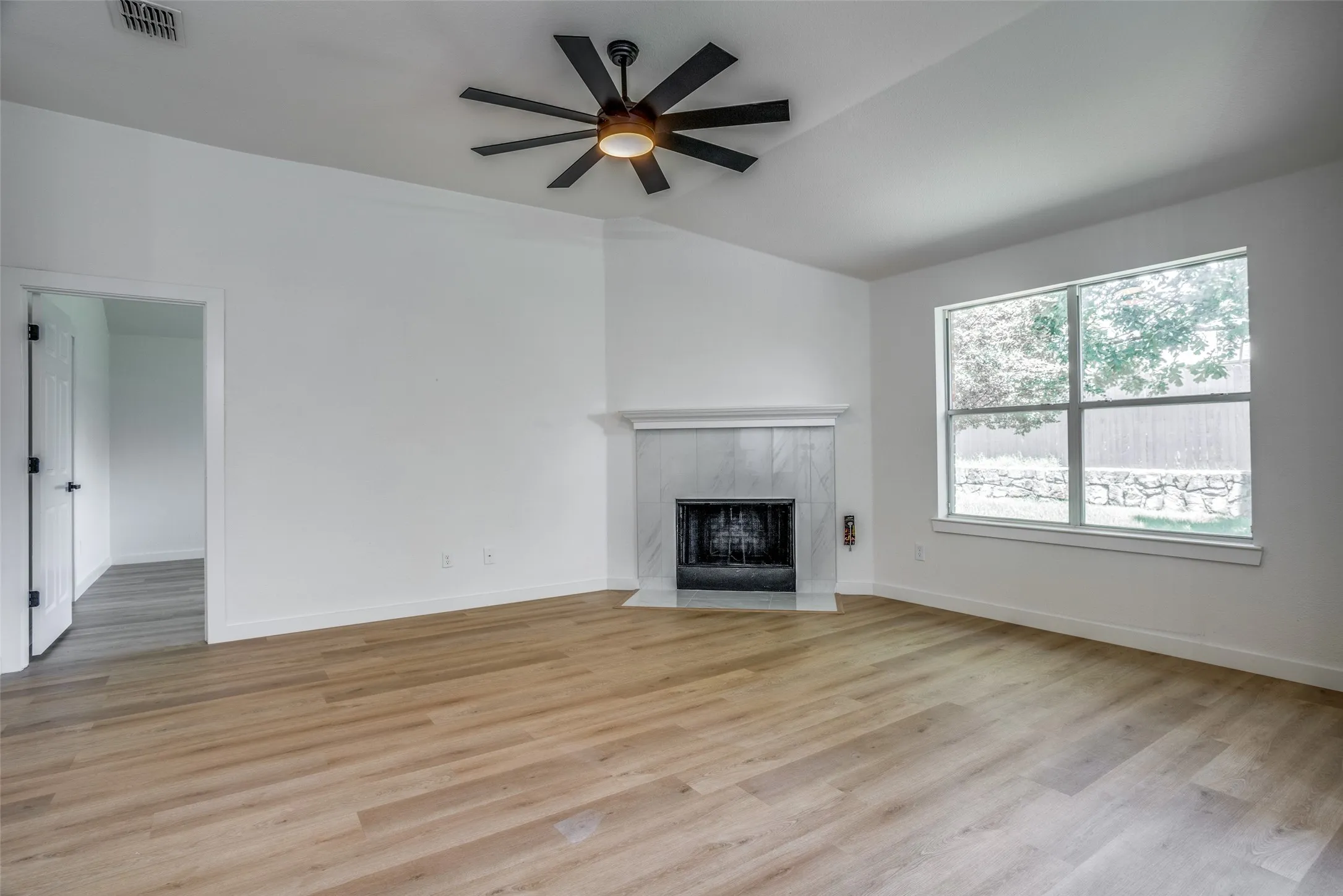 Unfurnished living room featuring ceiling fan, light hardwood / wood-style flooring, and a fireplace