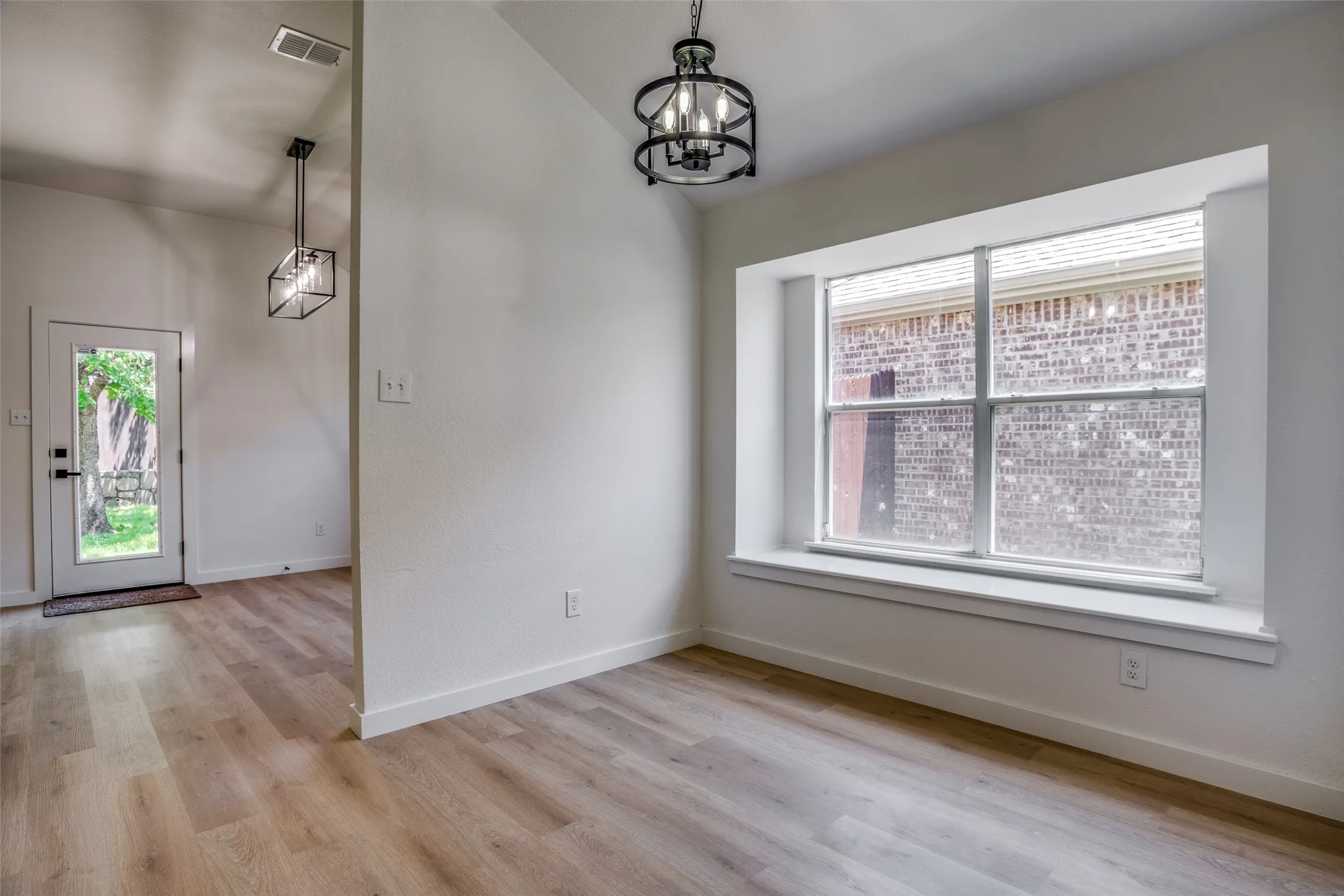 Unfurnished room featuring an inviting chandelier and light hardwood / wood-style flooring
