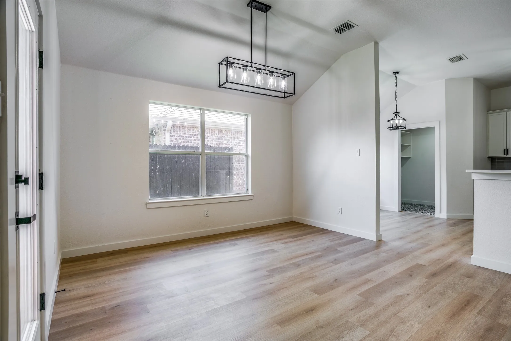 Unfurnished dining area with vaulted ceiling, light wood-type flooring, and a chandelier