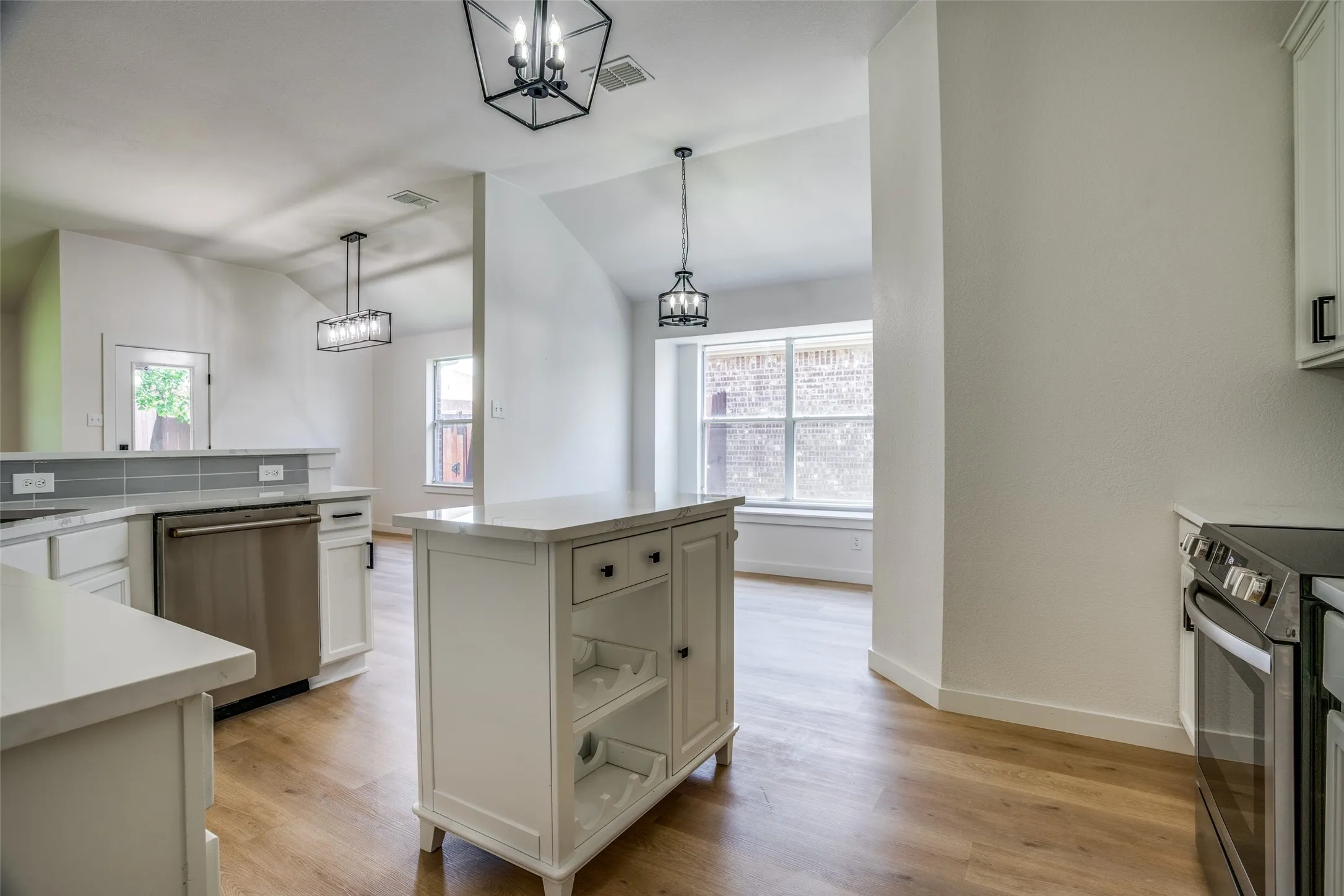 Kitchen with hanging light fixtures, a center island, stainless steel appliances, and light hardwood / wood-style flooring