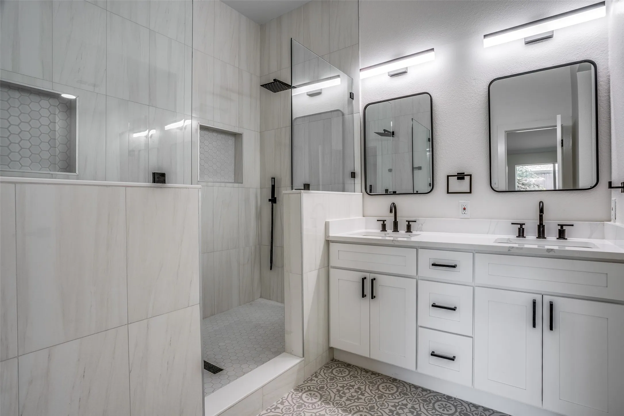 Bathroom featuring a tile shower, tile flooring, large vanity, and double sink