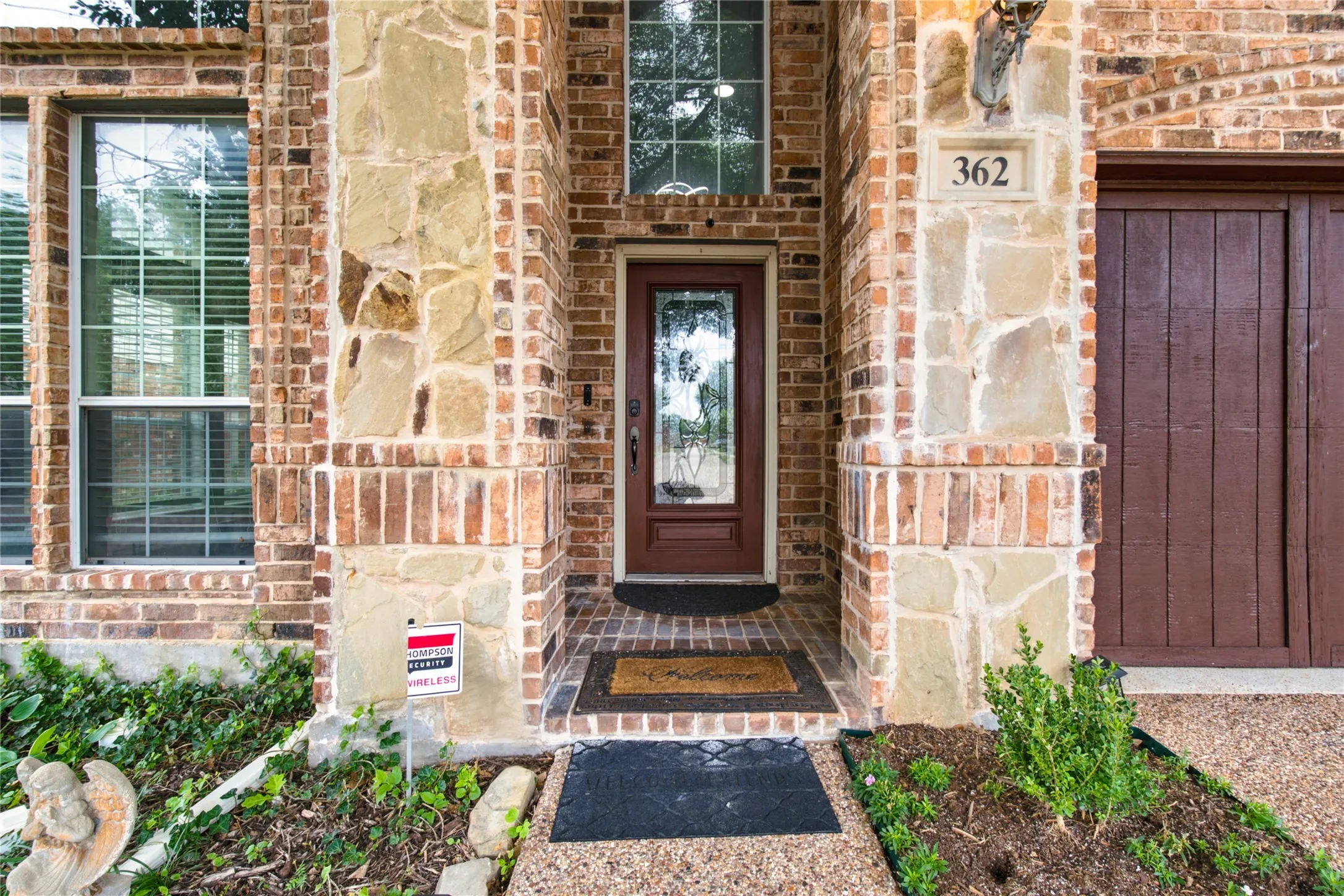 Brick and stone facade featuring a recessed entry with a glass-paneled door