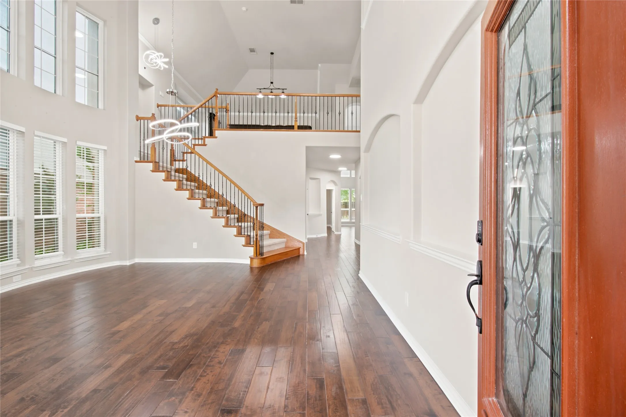 Grand entry with wood-finish flooring extending throughout, featuring a prominent staircase with wood banister and white spindles, and a second-story overlook