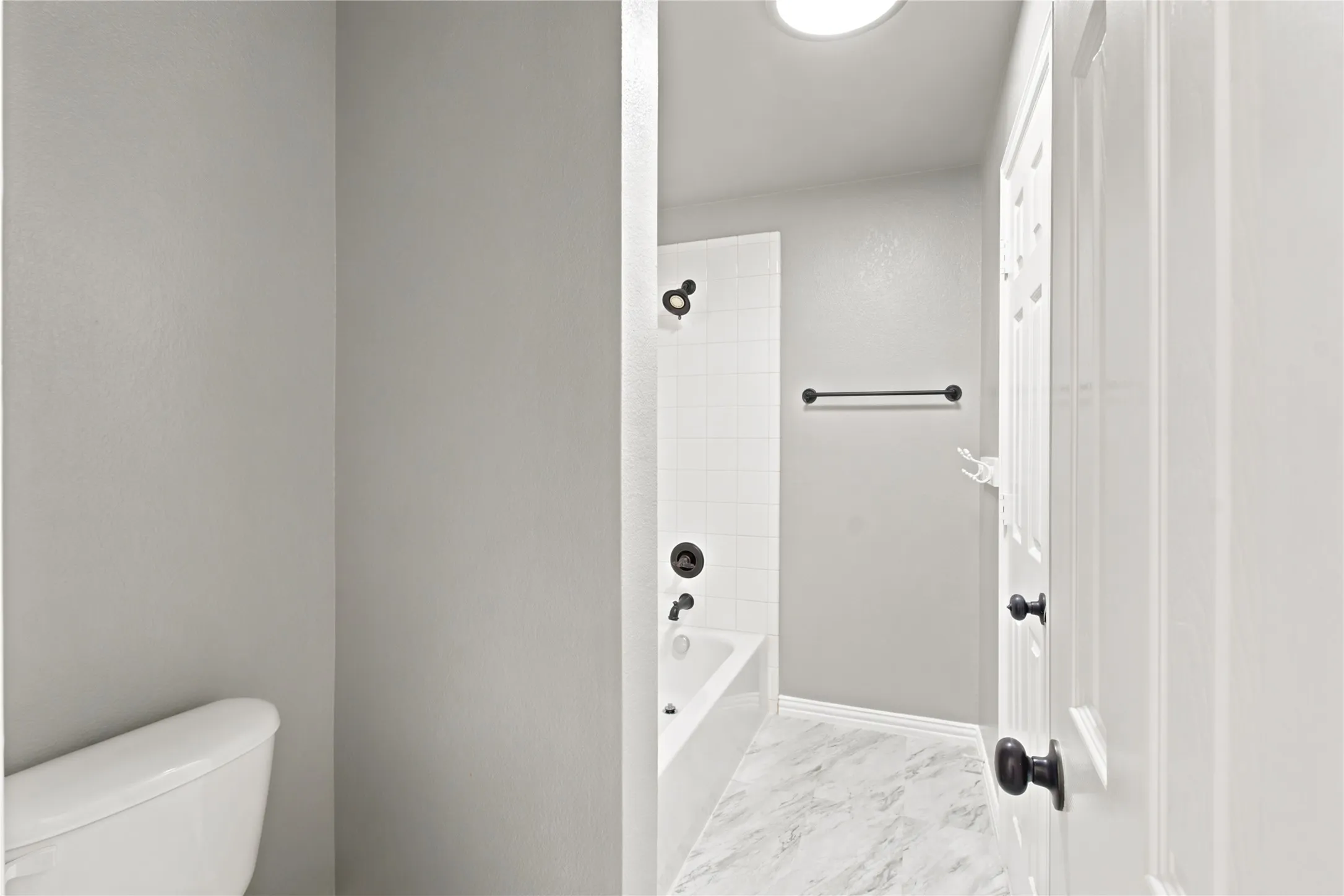 Bathroom featuring a white subway tile shower surround, a white bathtub, and a dark bronze shower fixture