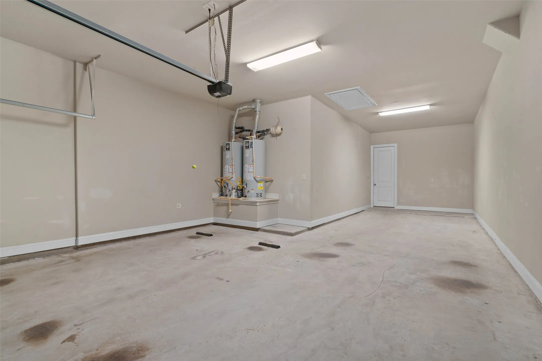Spacious garage featuring a concrete floor, painted walls, and overhead fluorescent lighting