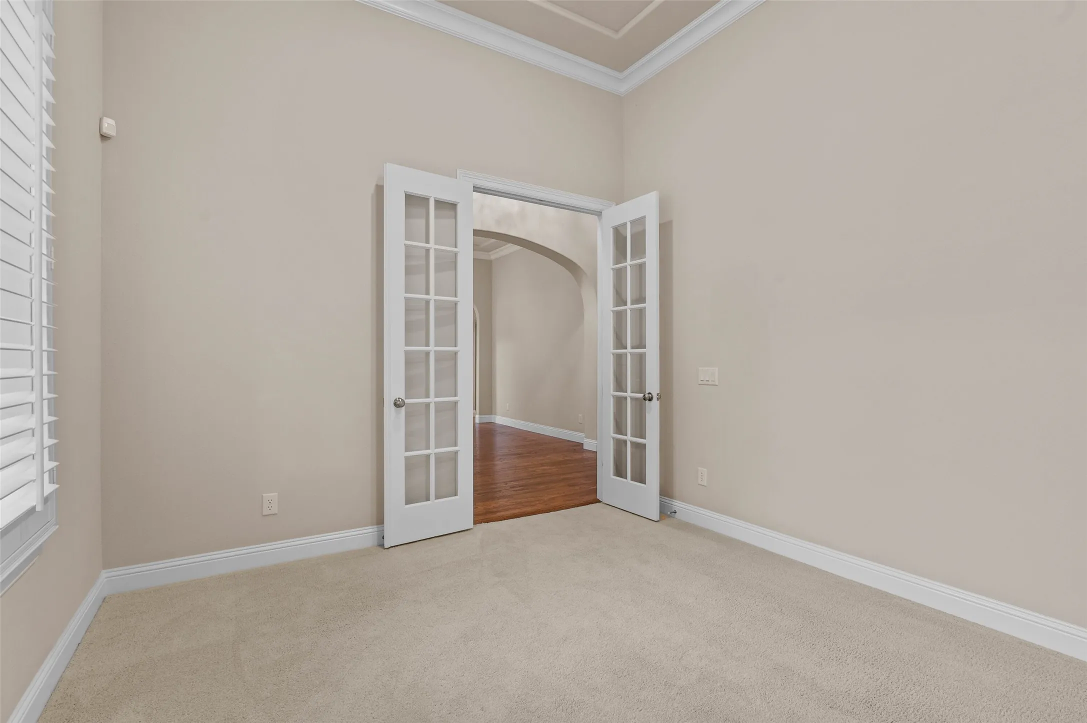 Dedicated office space featuring carpeted flooring, crown molding and large windows with plantation shutters.