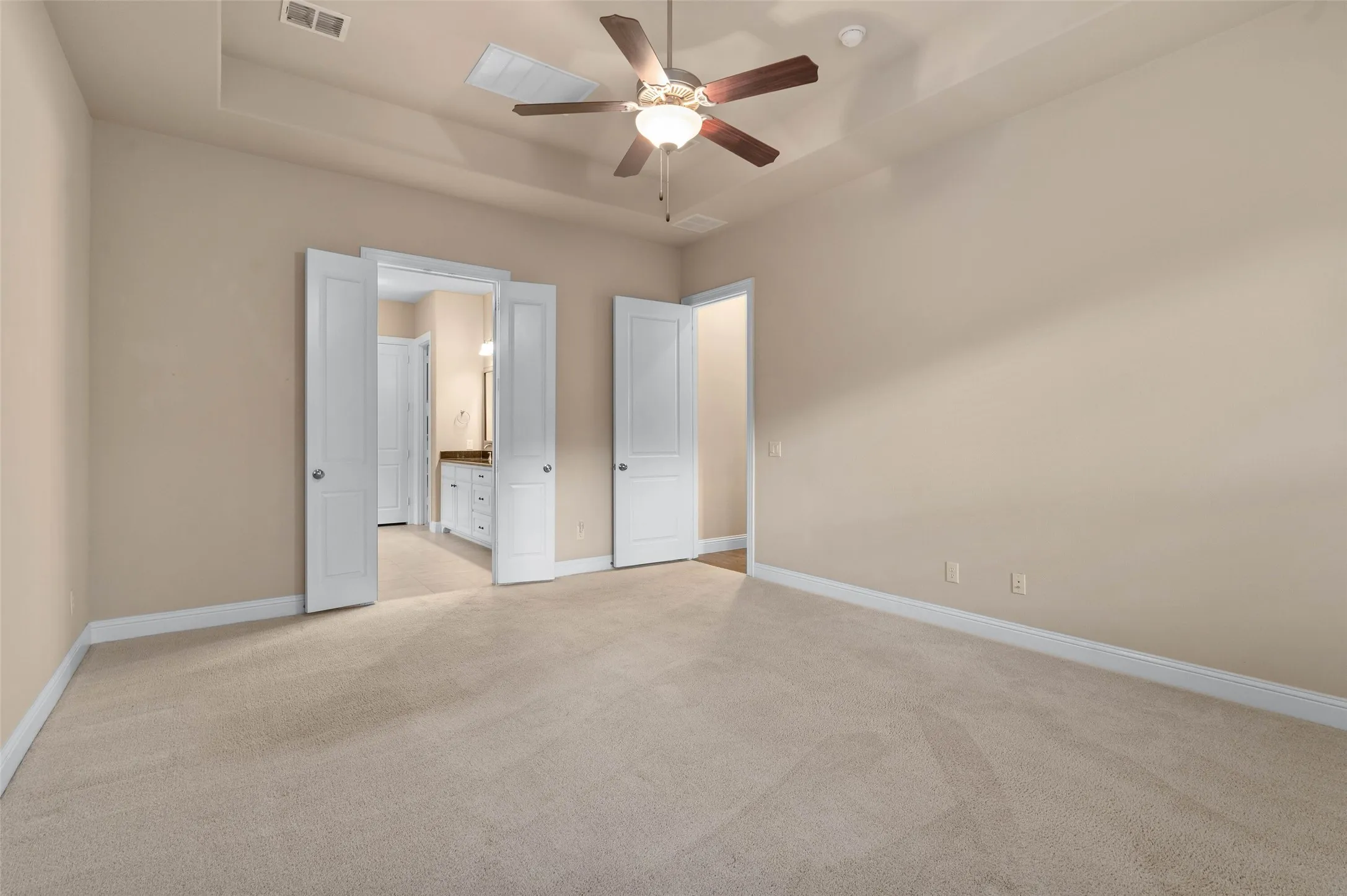 Primary bedroom with carpeted flooring, ceiling fan and en-suite bath.