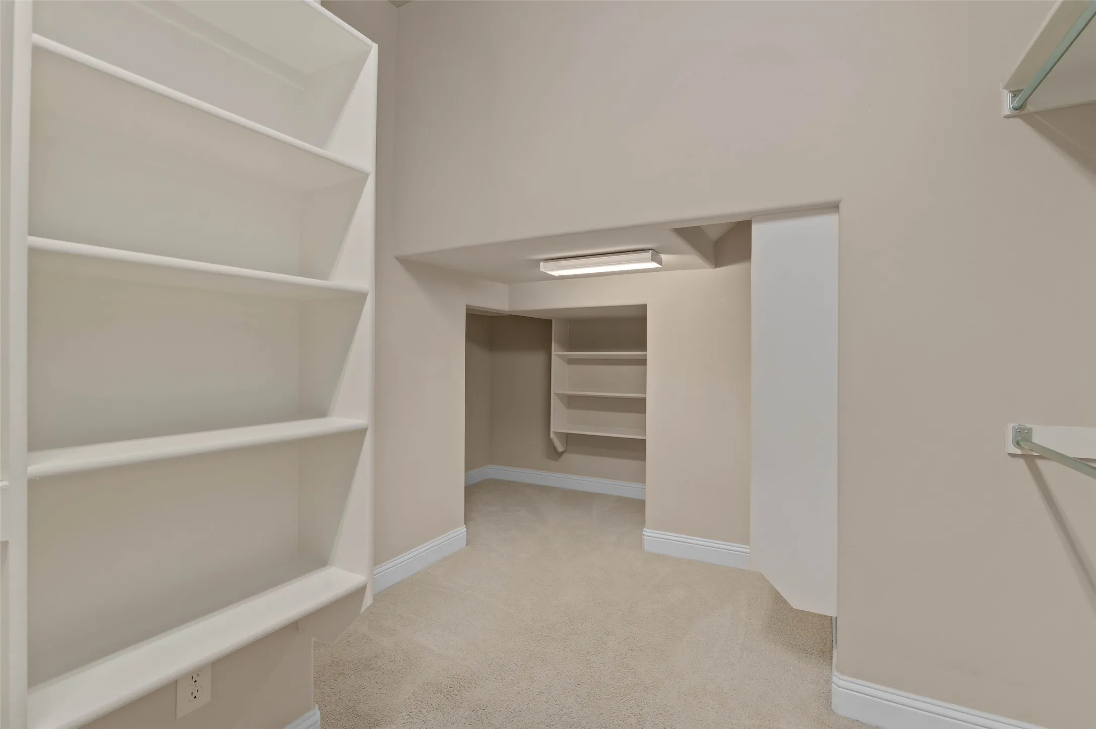 Expansive walk-in closet featuring multiple built-in shelving units, wall-mounted hanging rods, recessed lighting, and soft carpet flooring