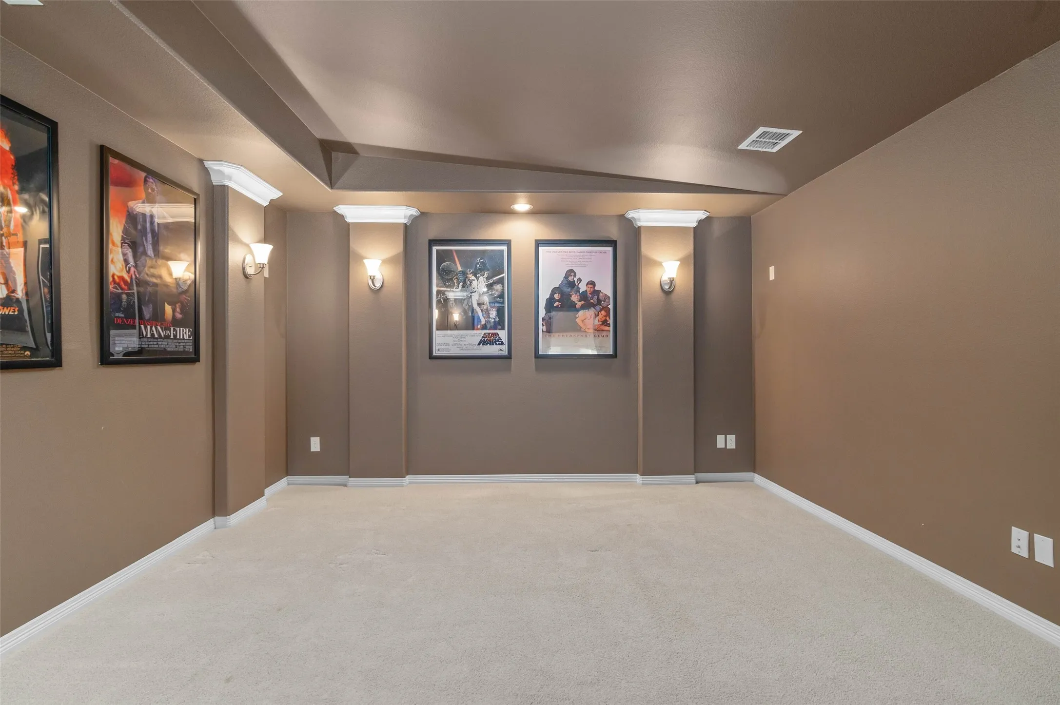 Large, carpeted media room with build in sconce lighting.