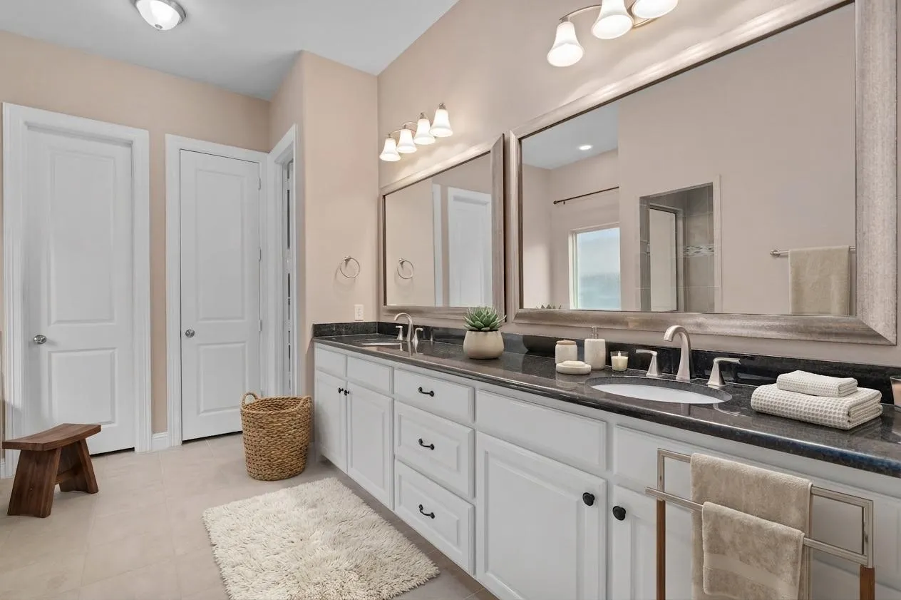 Virtually staged primary bathroom with granite tops, double vanity and garden tub.