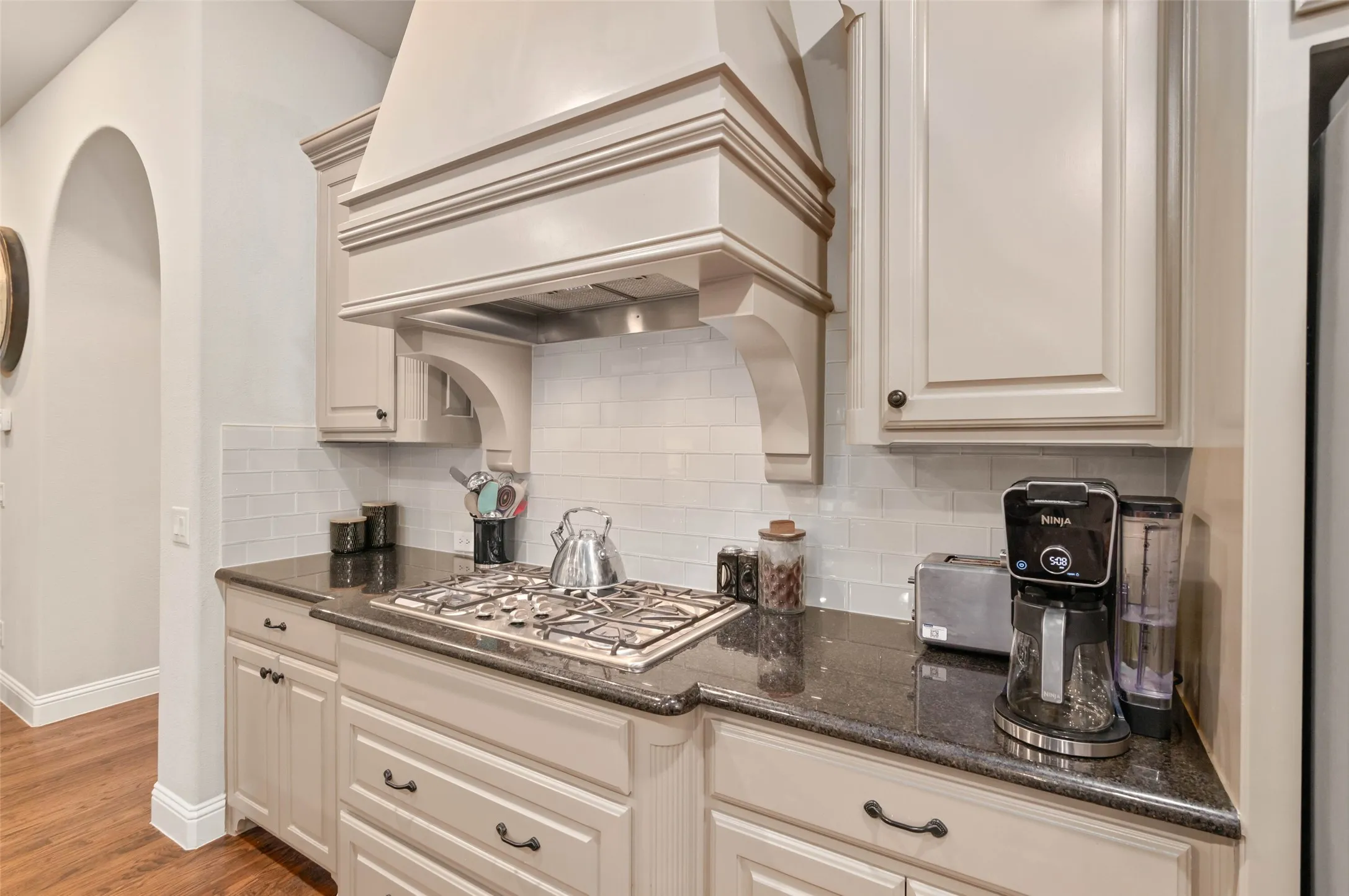 Kitchen featuring custom vent, granite cabinets and large kitchen island.