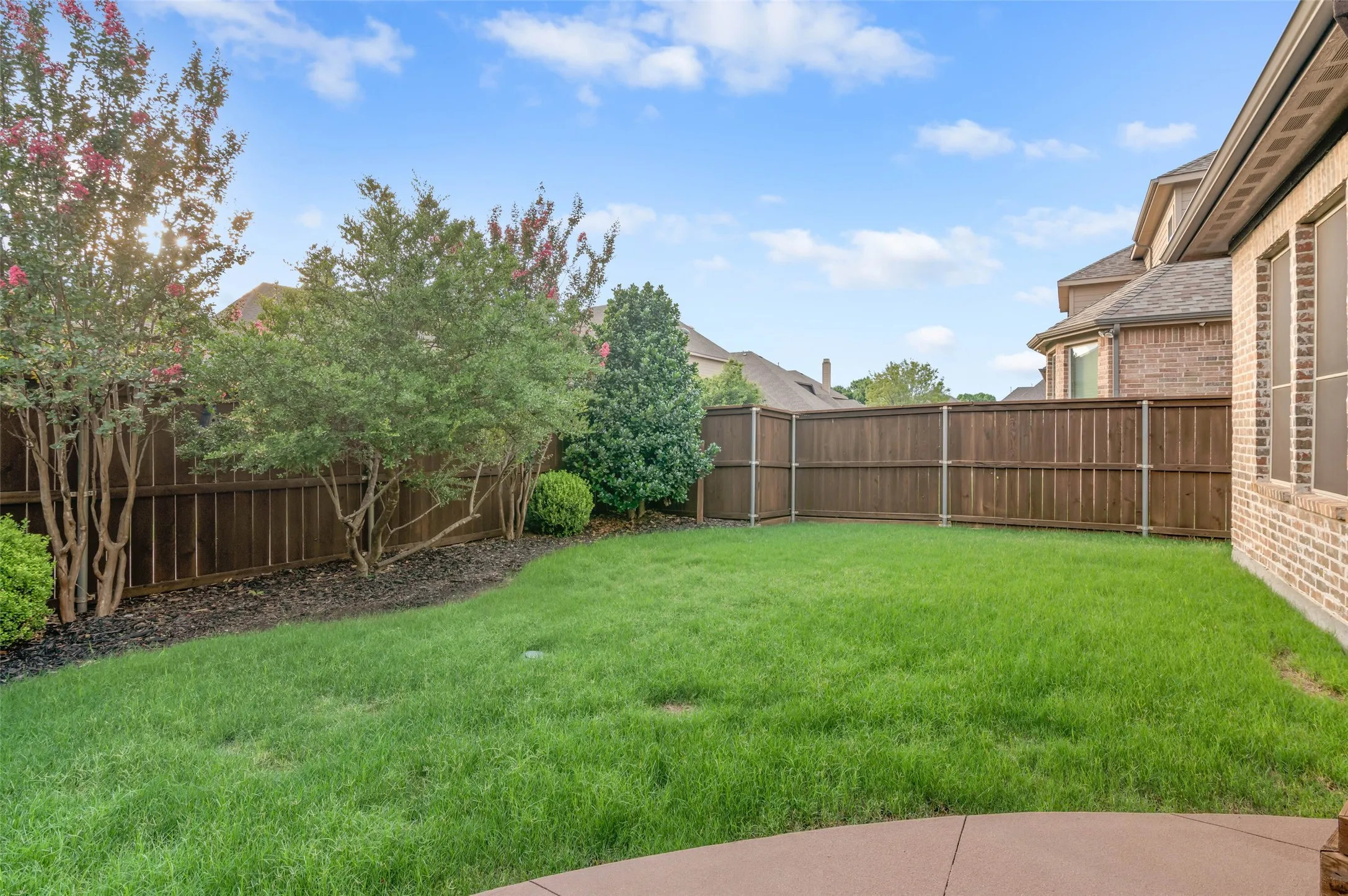 Expansive backyard featuring a lush lawn, natural landscaping, and a privacy fence