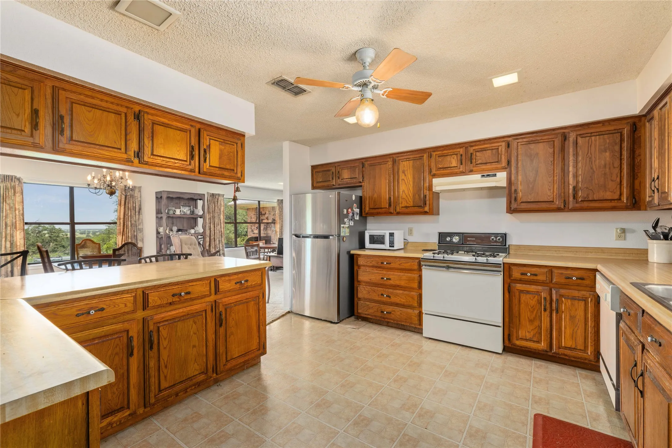 Kitchen featuring wood cabinetry, solid surface countertops, tile flooring, and a ceiling fan