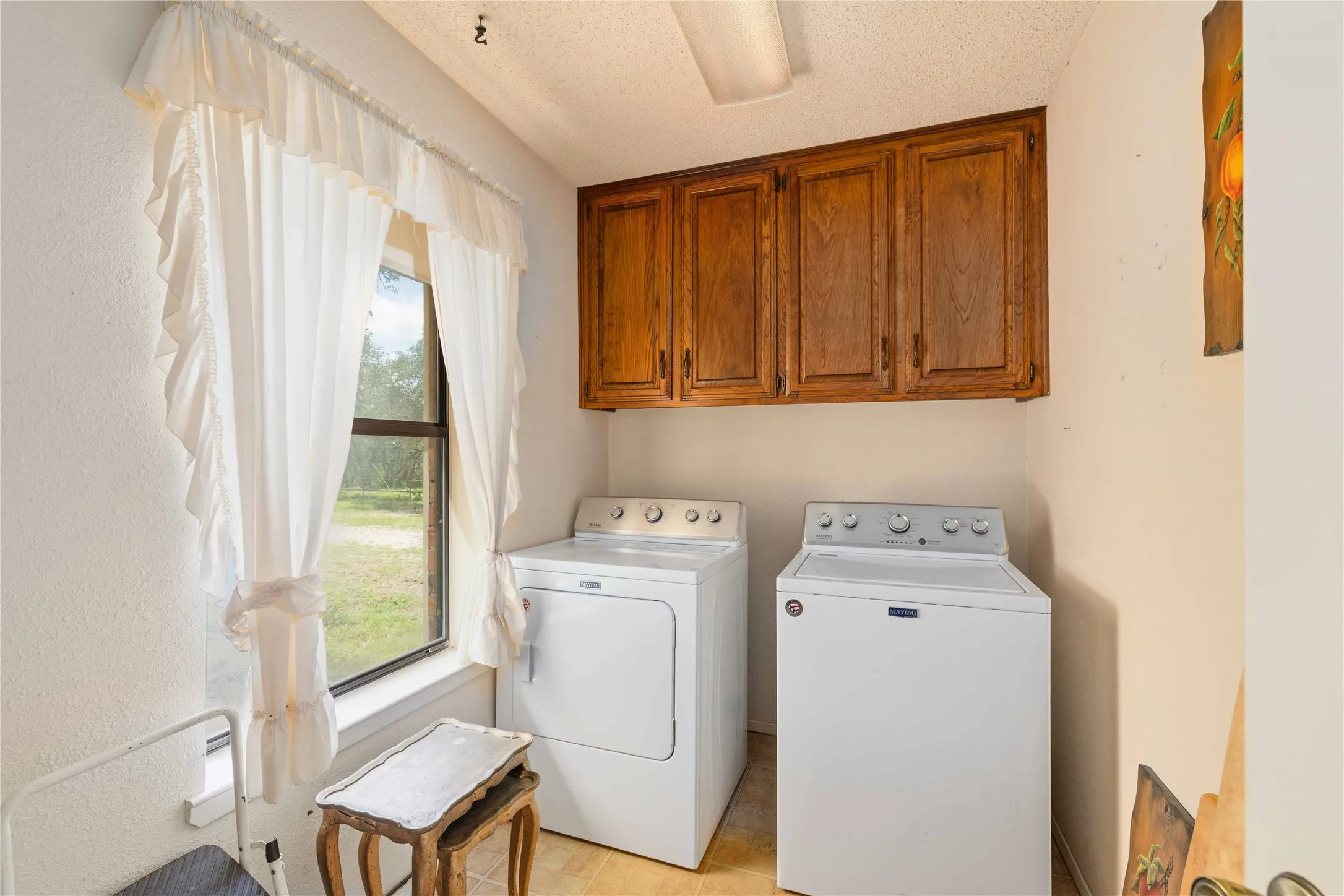 Utility space featuring upper wood cabinetry and a window providing natural light