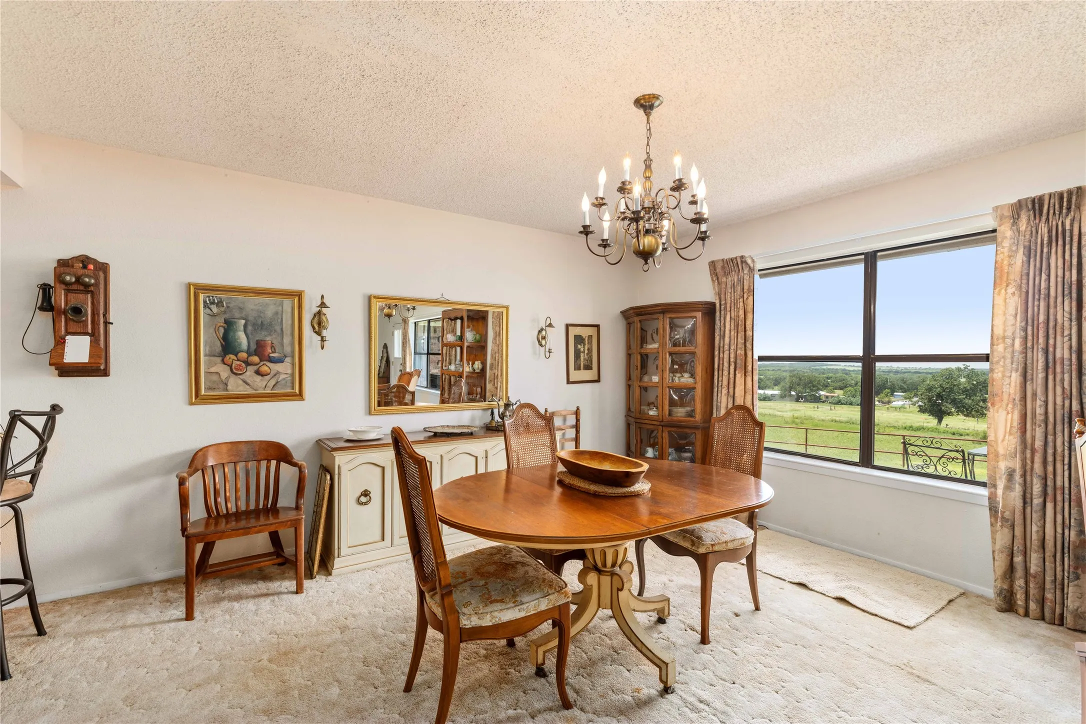 Dining area featuring a prominent window, a metal chandelier, light-colored carpeting, and white walls