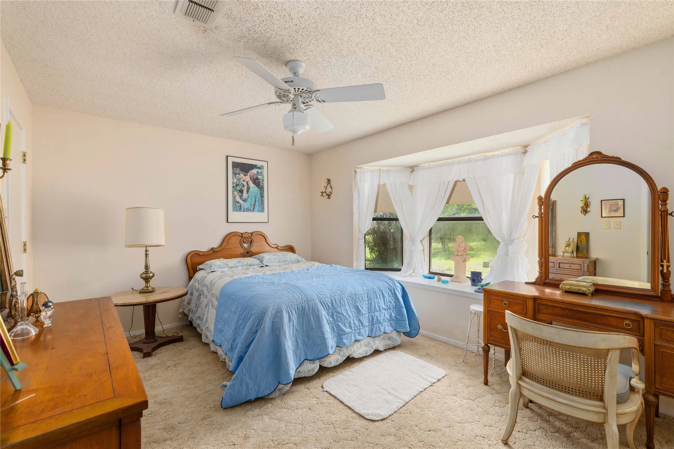 Bedroom featuring a bay window, wall-to-wall carpeting, and a ceiling fan with light fixture