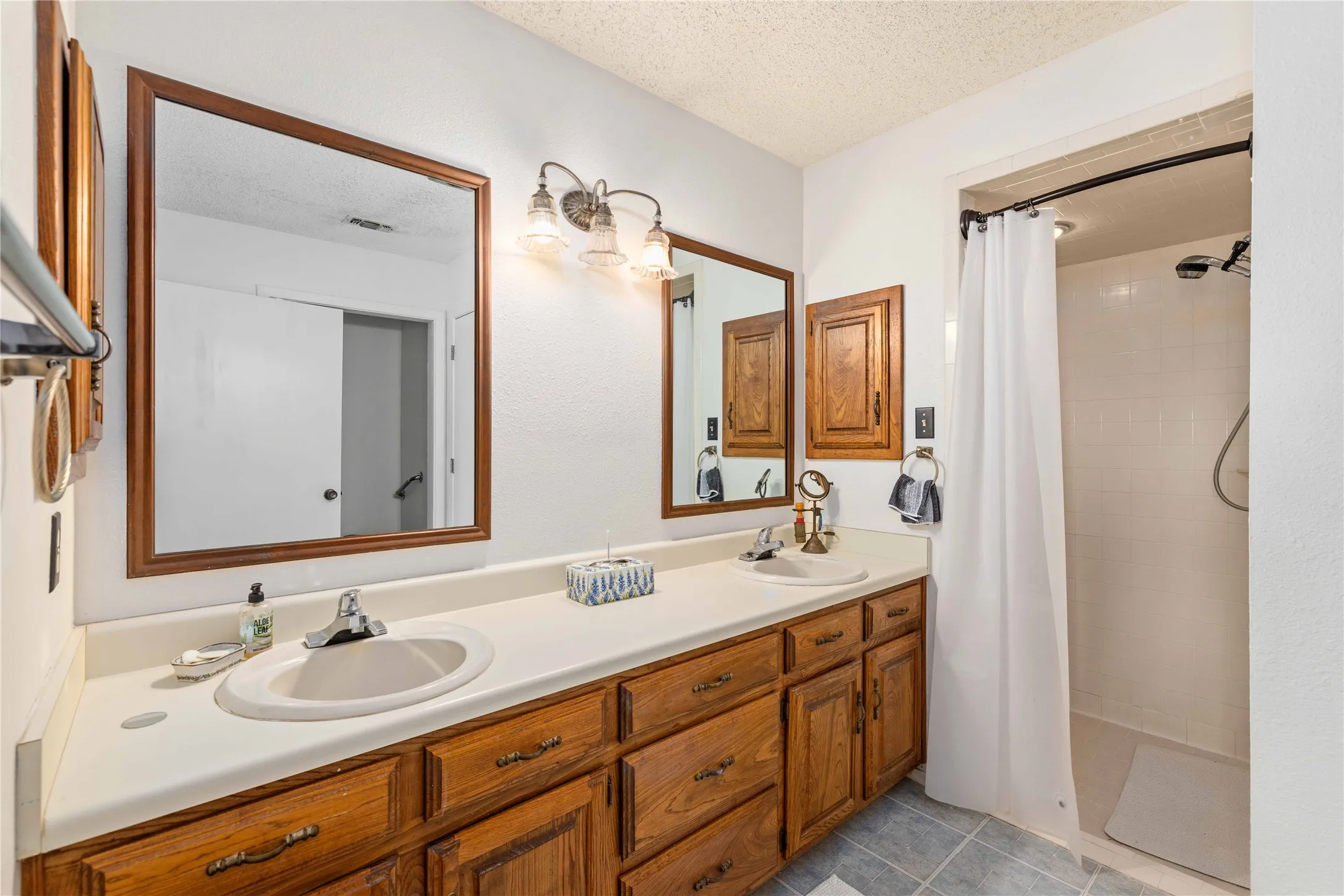 Dual vanity with wood-finish cabinetry and white countertops