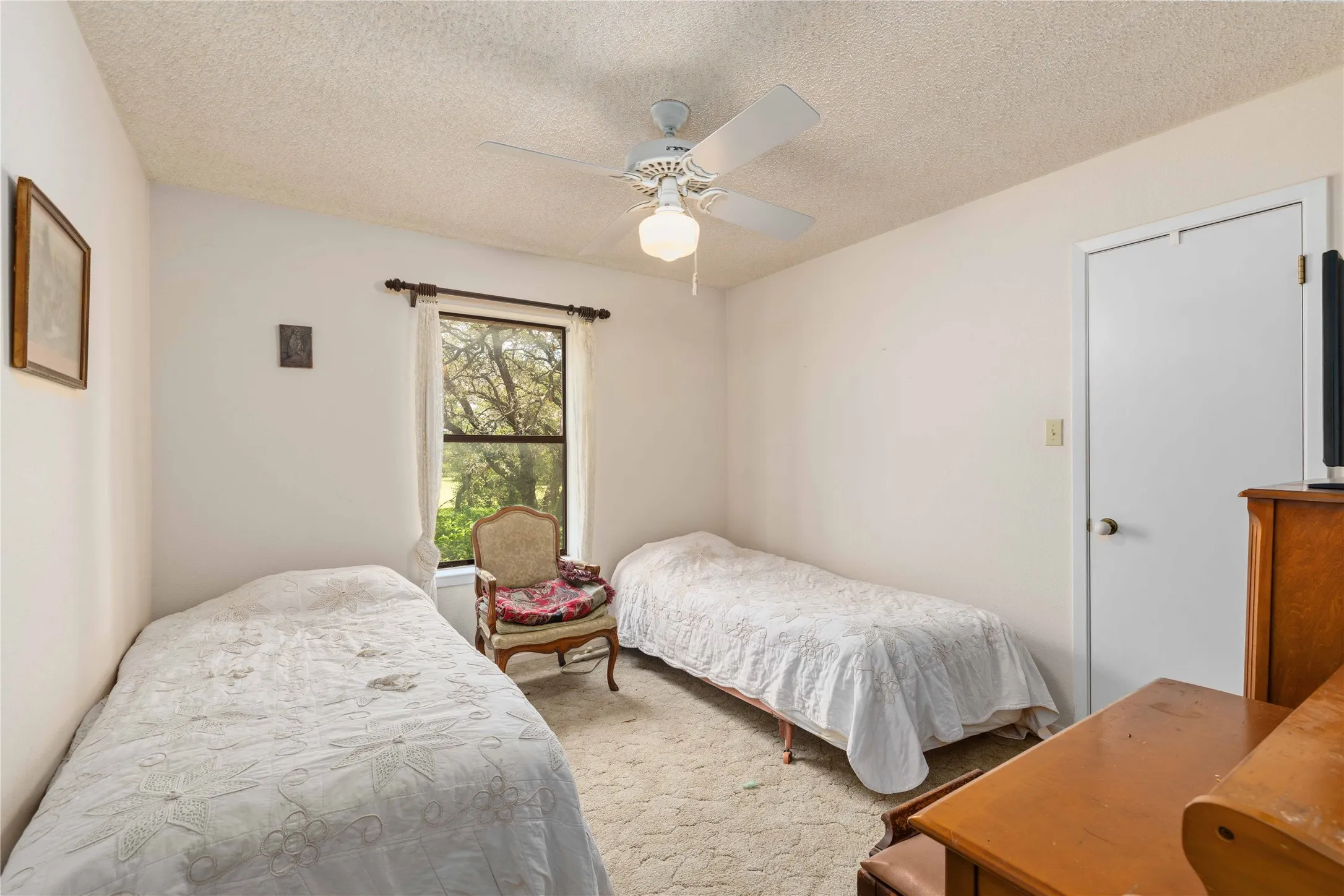 Carpeted room featuring a ceiling fan with integrated lighting, a window with a dark frame, and a white interior door