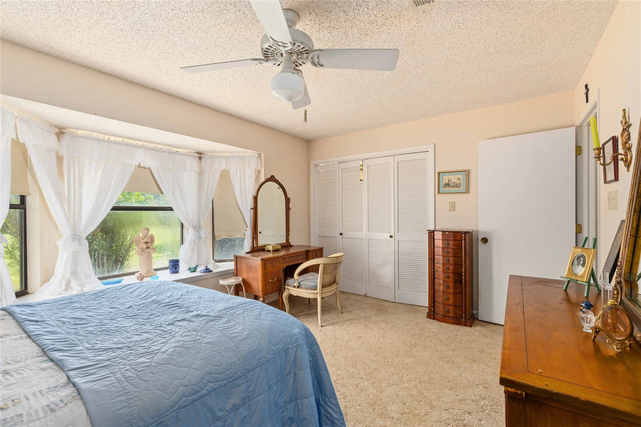 Bedroom featuring a bay window, ceiling fan, and bi-fold closet doors