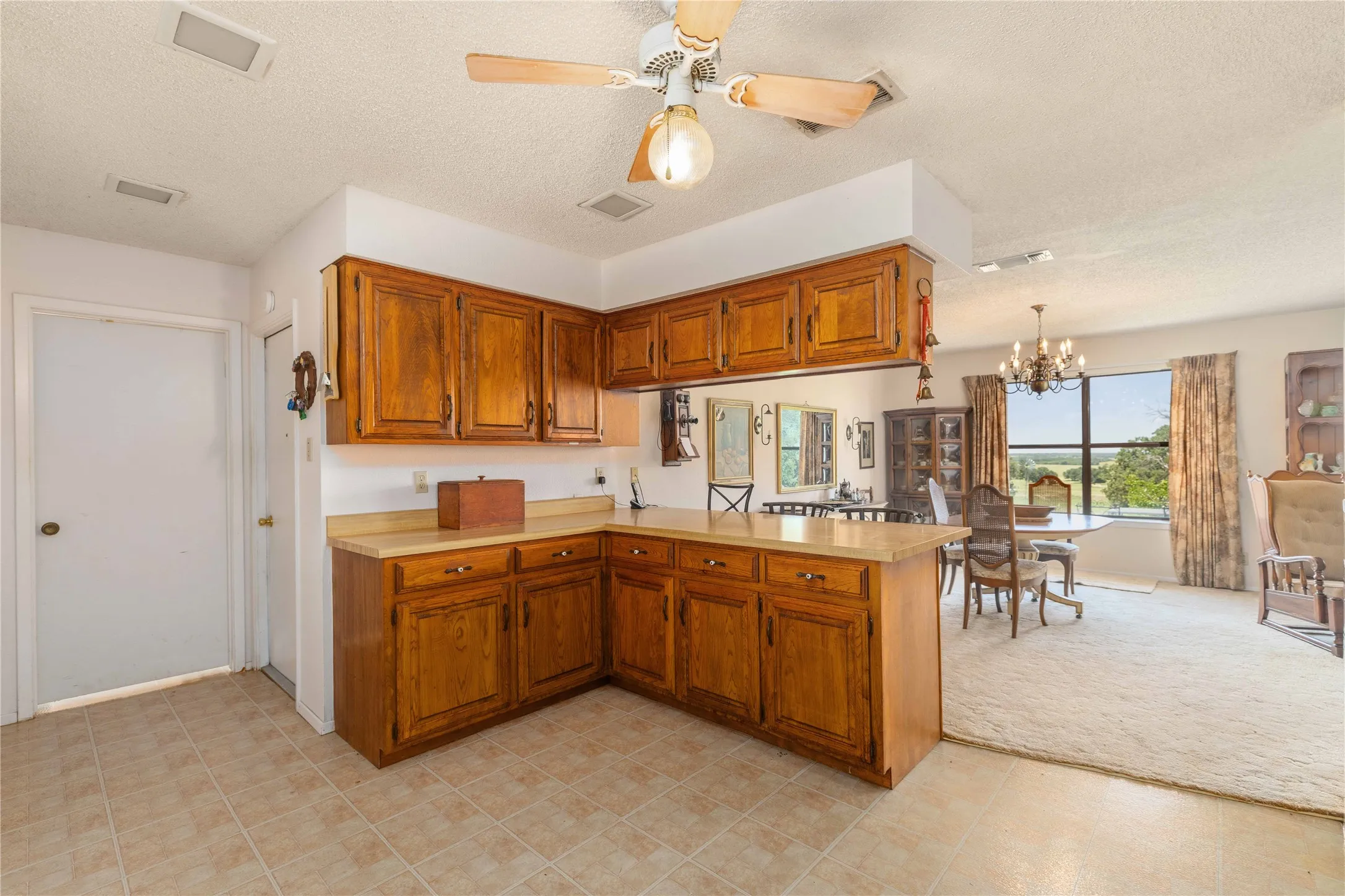 Kitchen featuring wood cabinetry, light-toned countertops, and tile flooring