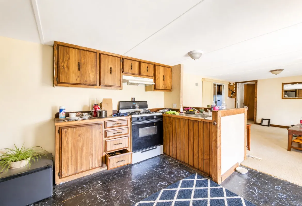 Kitchen area featuring wood-finish cabinetry, a freestanding range, and black-patterned flooring