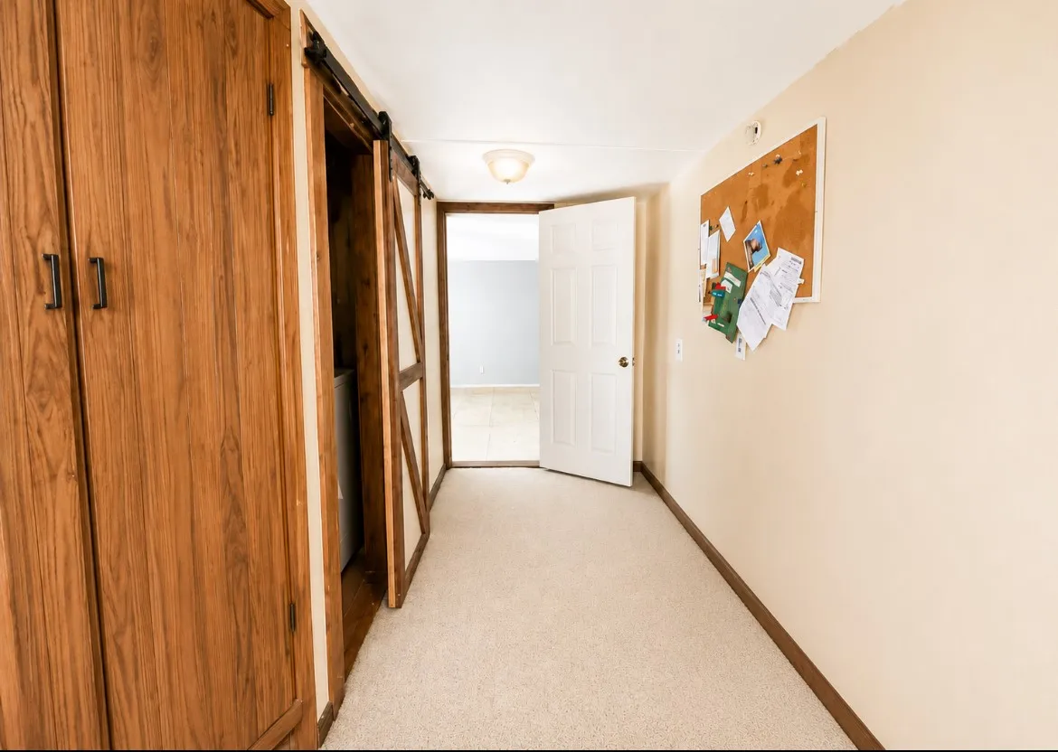 Hallway featuring light-colored carpeting and beige painted walls