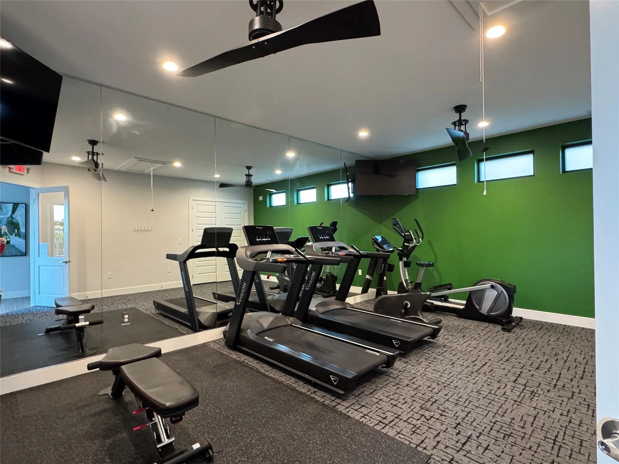 Dedicated fitness space featuring full-wall mirrors, recessed lighting, and ceiling fans