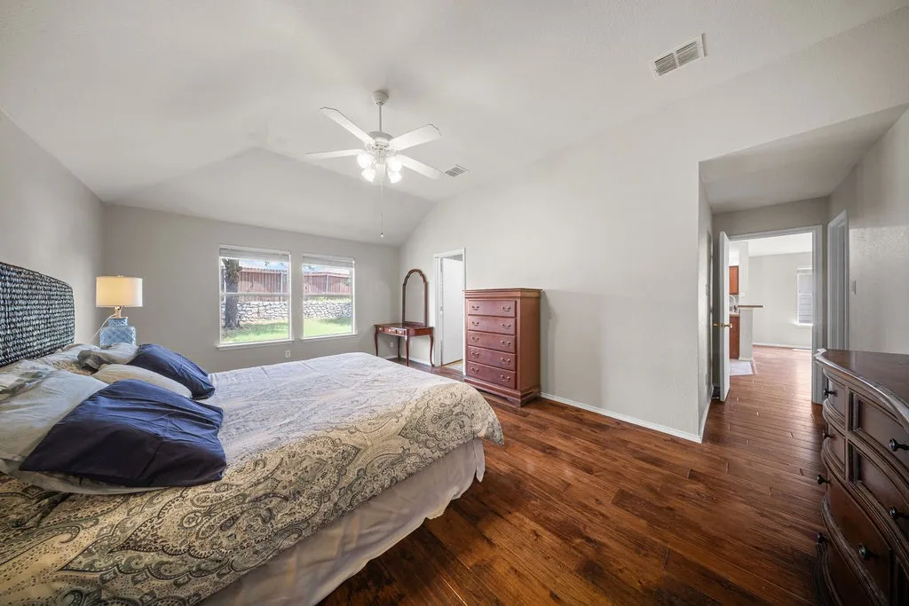 Spacious room featuring vaulted ceilings, wood-finish flooring, and a ceiling fan