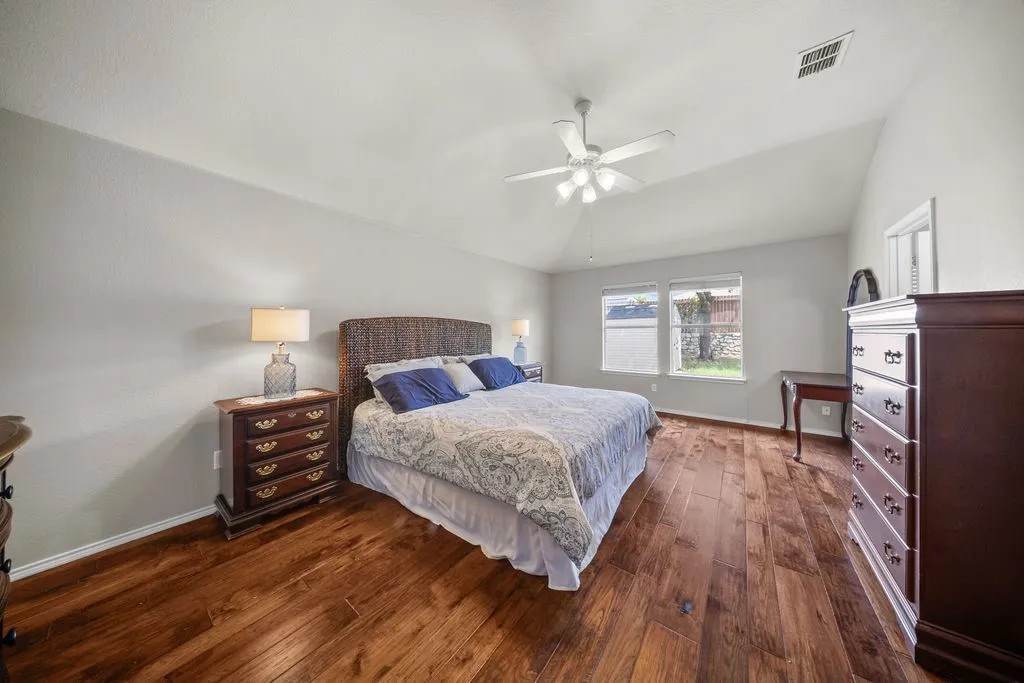 Spacious room featuring rich wood-finish flooring, vaulted ceilings, and two large windows