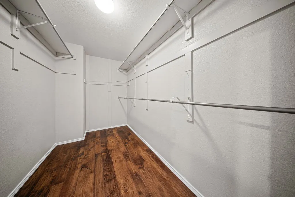 Walk-in closet featuring wood-finish flooring, white walls, and built-in shelving with hanging​​‌​​​​‌​​‌‌​‌‌​​​‌‌​‌​‌​‌​​​‌​​ rods
