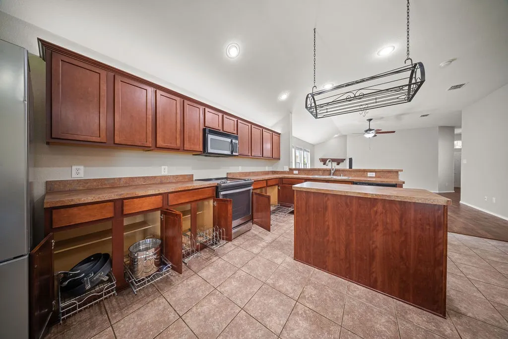 Kitchen featuring wood-finish cabinetry, stainless steel appliances, a center island with a breakfast bar, and tile flooring