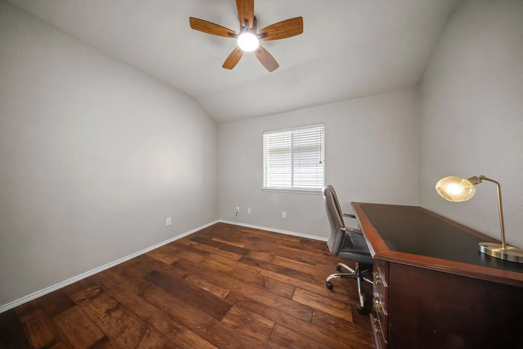 Room featuring wood-finish flooring, a ceiling fan, and a window with horizontal blinds