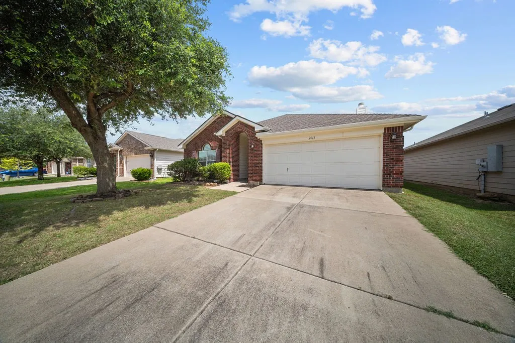 Brick exterior residence featuring an attached garage with a white door