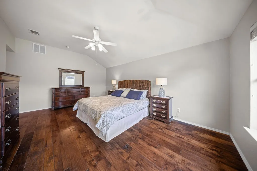 Bedroom featuring wood-finish flooring, vaulted ceiling, and a ceiling fan
