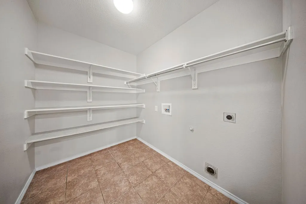 Utility room with neutral wall paint and ceramic tile flooring